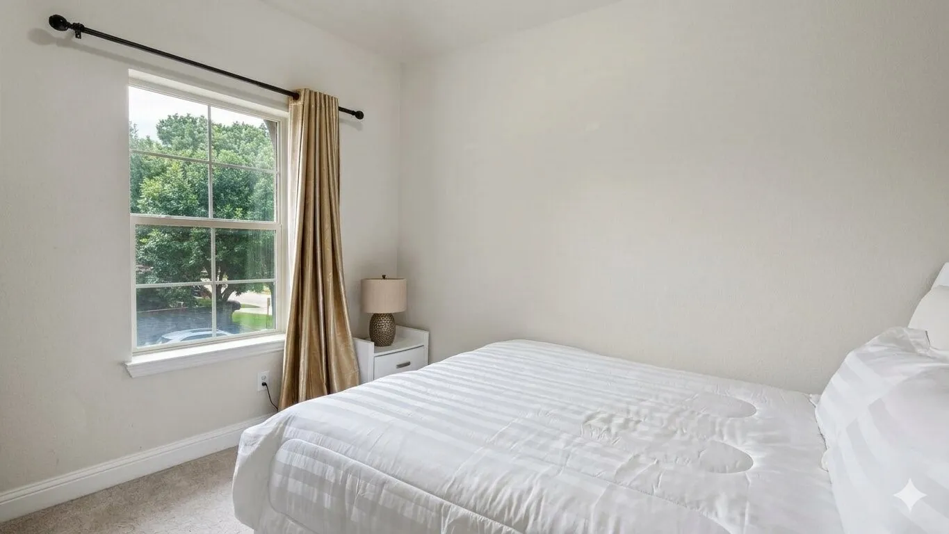 Double-hung window featuring a black curtain rod and light-colored drapes, set against light-toned walls