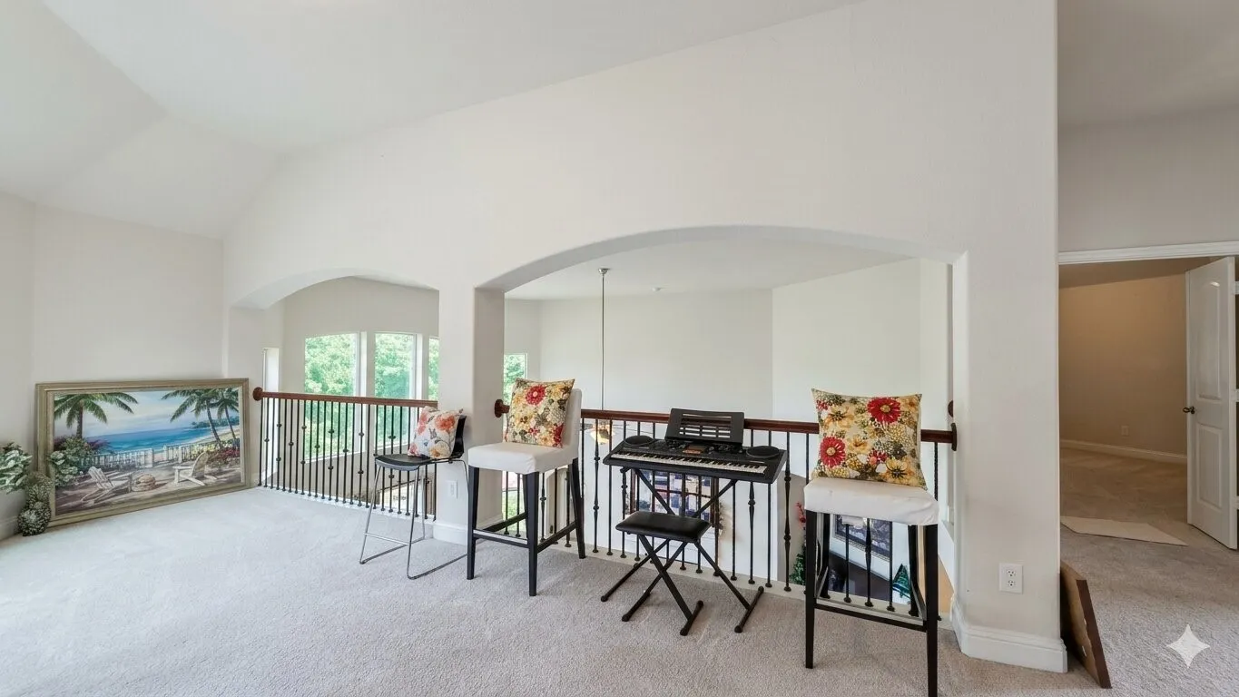 Carpeted loft area featuring arched entryways and a wrought iron balustrade with a wooden handrail