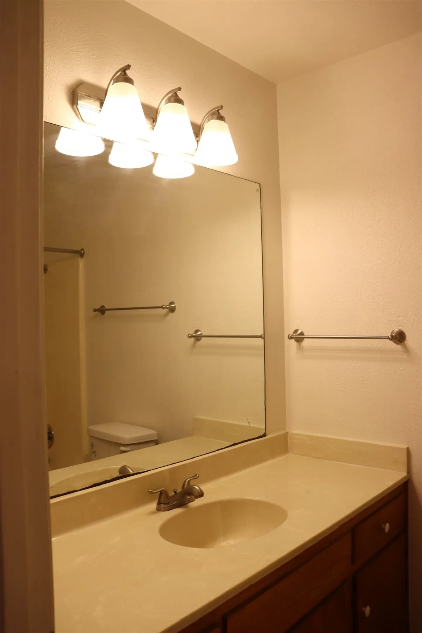 Bathroom vanity featuring a light-colored countertop, integrated sink, and wood-finish cabinetry