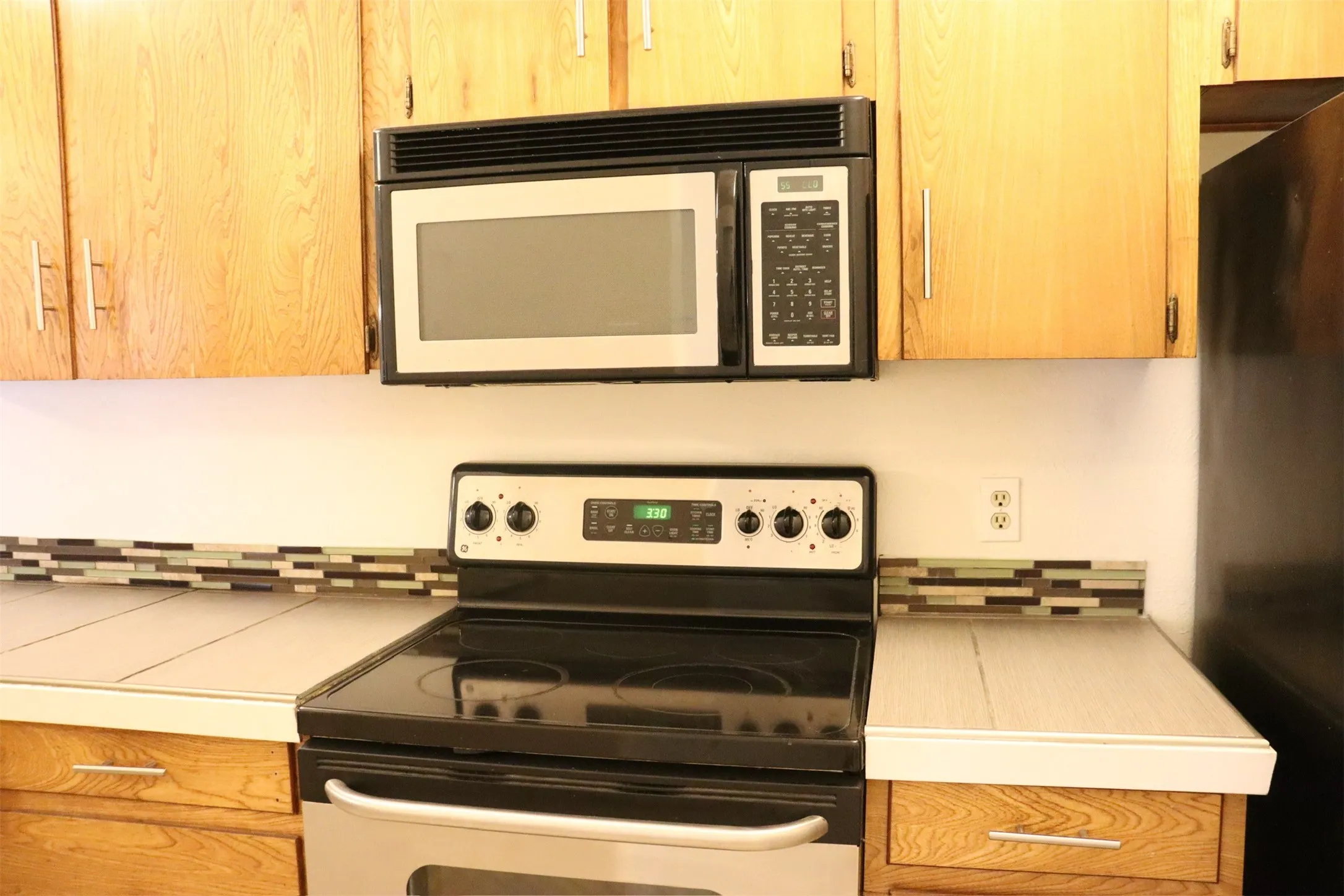 Kitchen with light wood-finish cabinetry and a mosaic tile backsplash