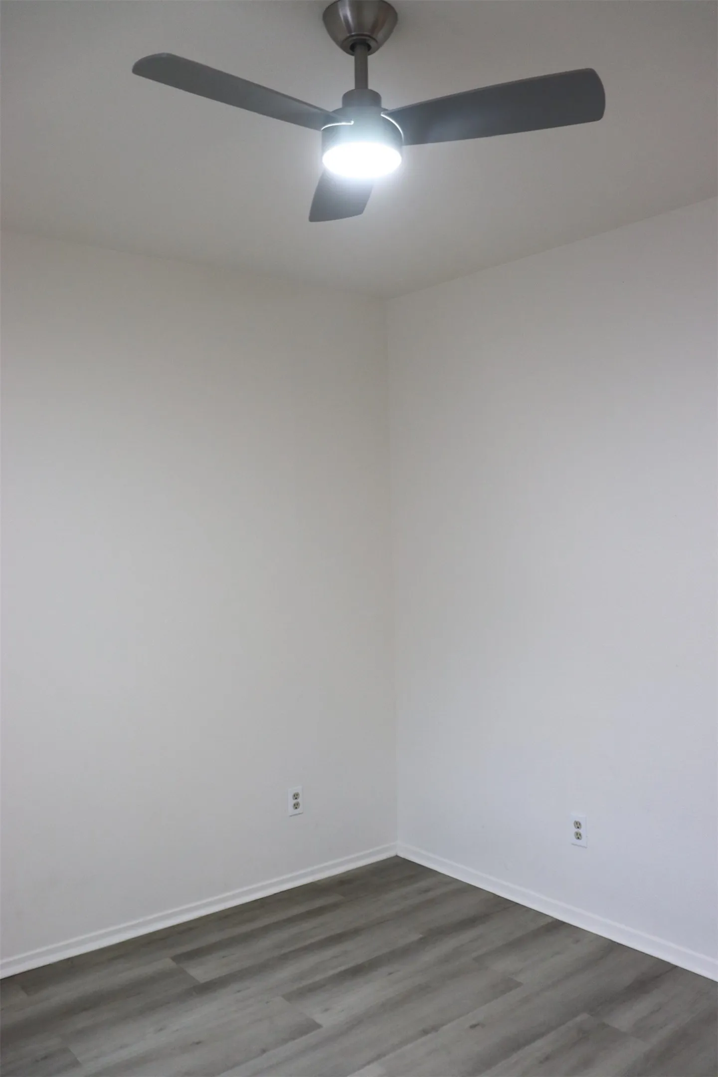 Brushed nickel ceiling fan with integrated lighting, wood-finish flooring, and crisp white walls