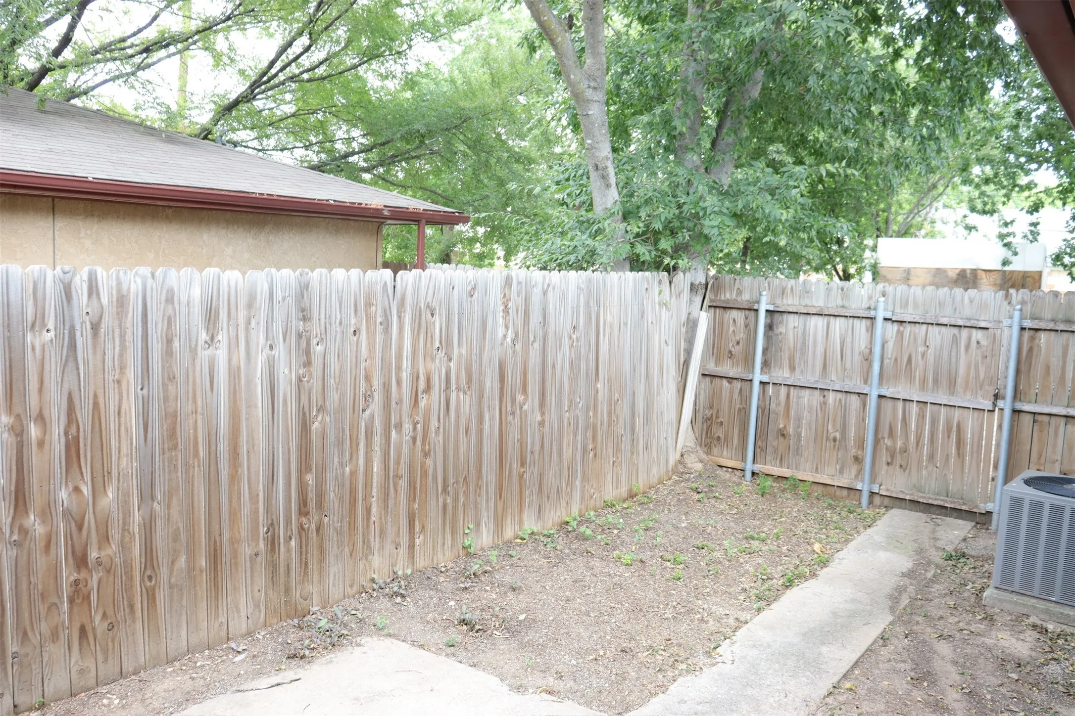 Private outdoor space featuring a wood fence, concrete patio, and mature trees
