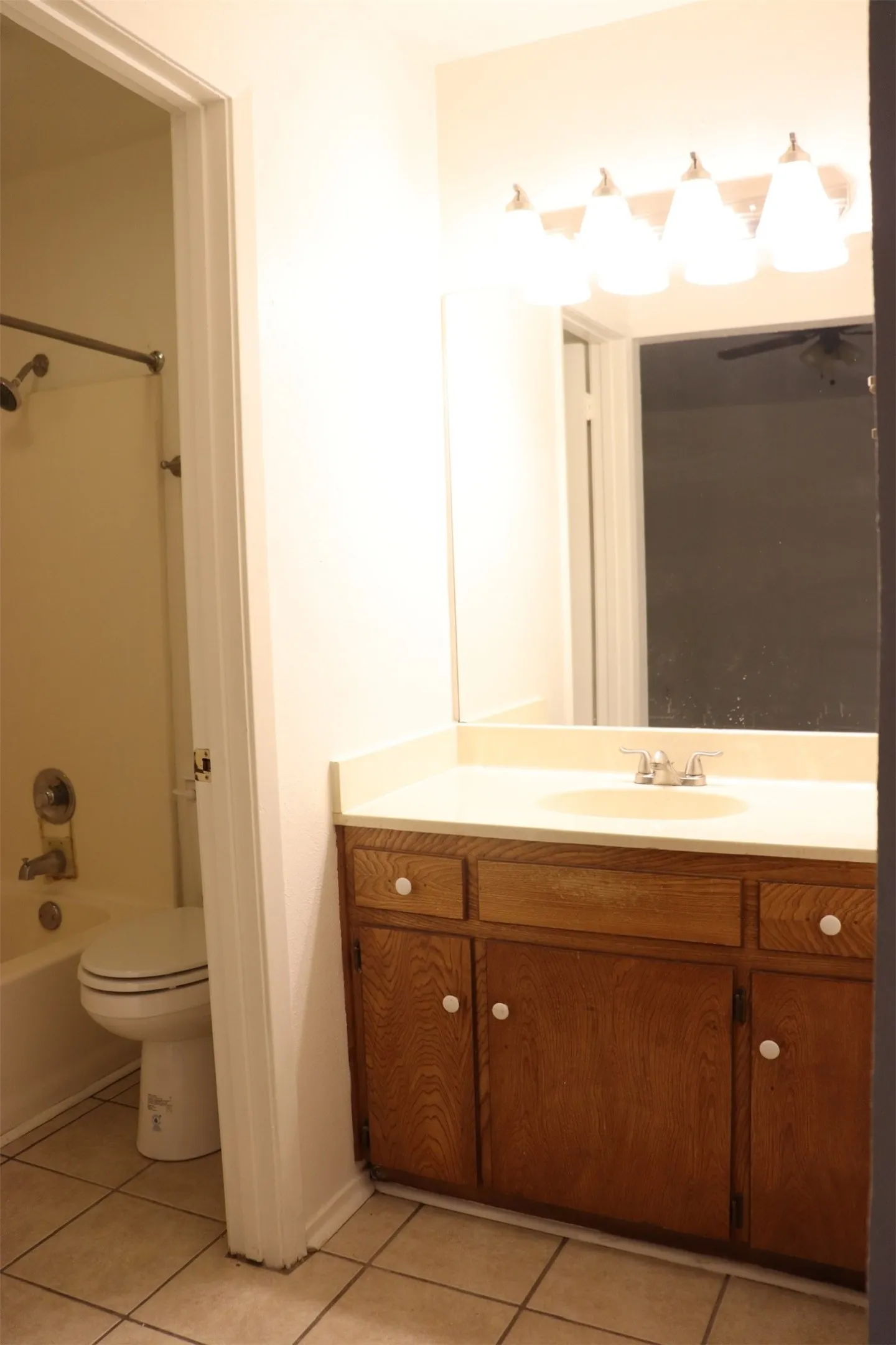 Bathroom vanity with wood-finish cabinetry, a light-toned countertop, and an integrated sink