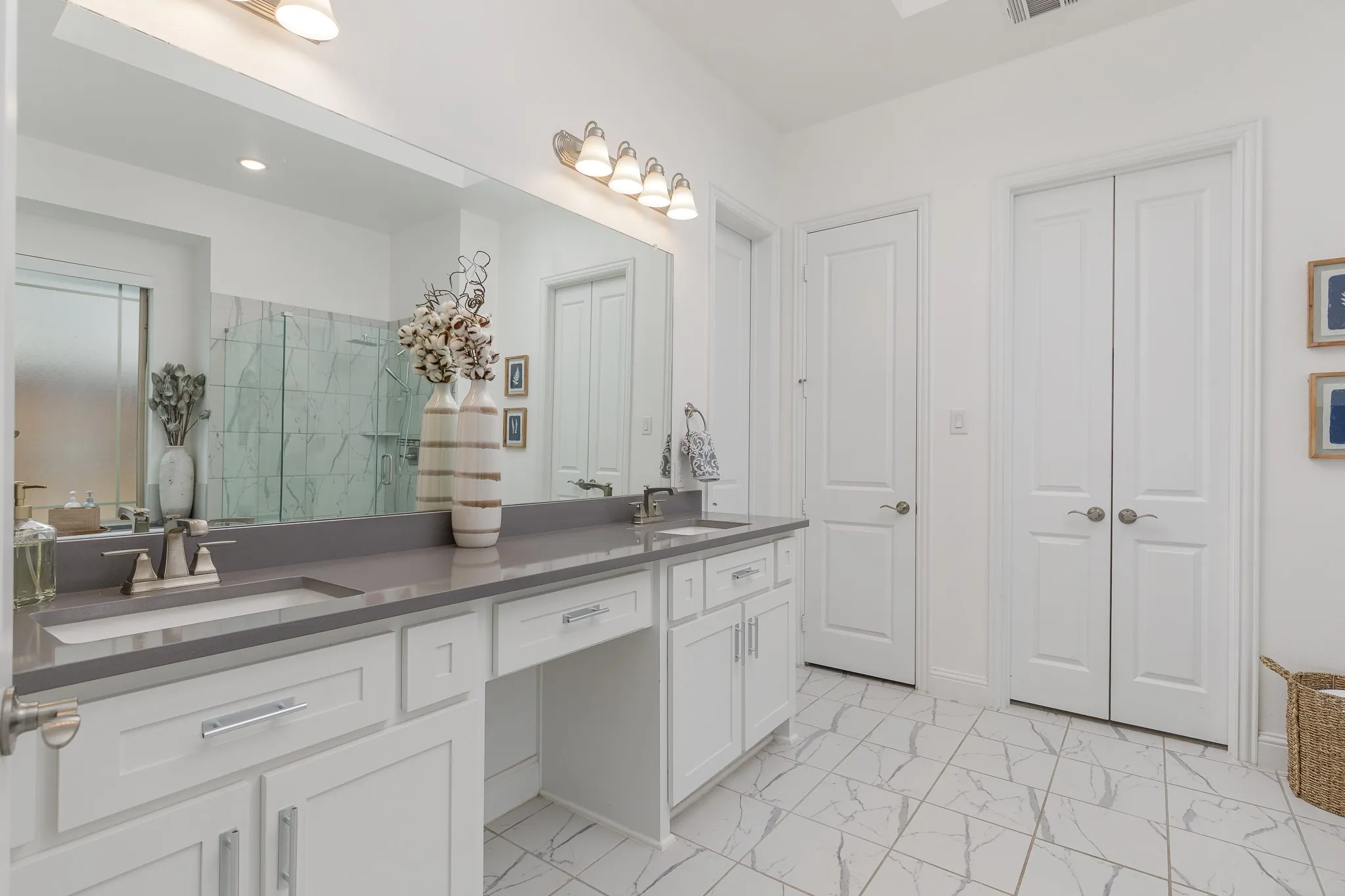Bathroom featuring a double vanity with stone countertops, integrated sinks, white cabinetry, and brushed nickel hardware