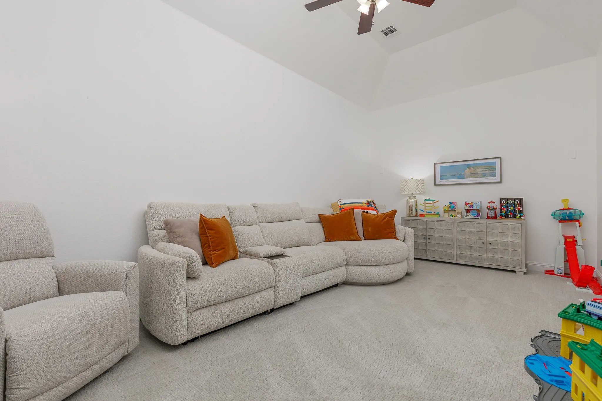 Spacious interior room featuring vaulted ceilings, light-colored carpeting, a ceiling fan, and ample wall space