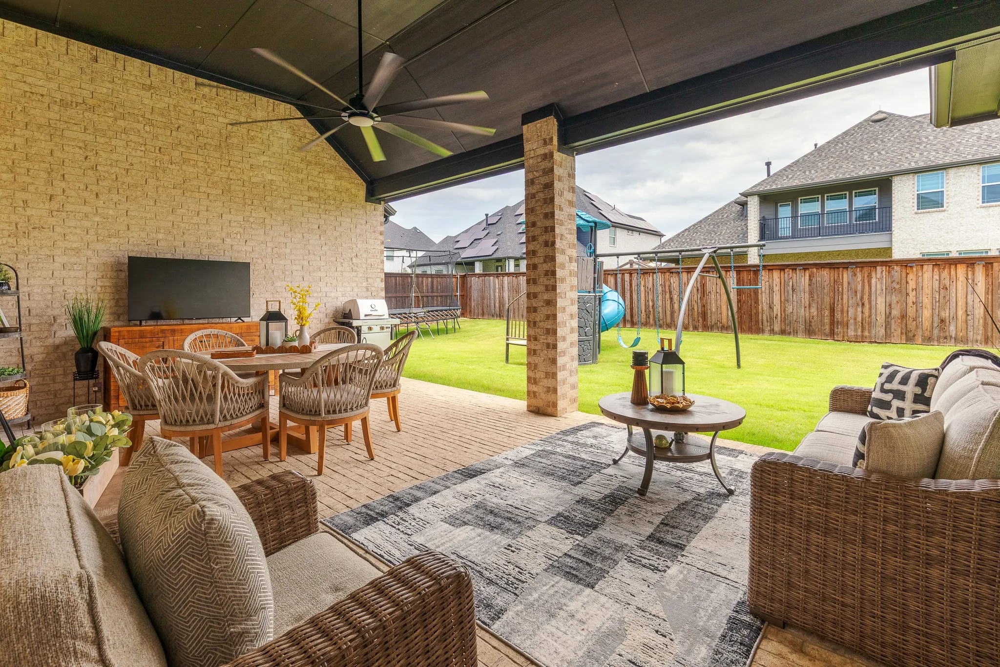 Expansive covered patio featuring light-toned brick walls, an outdoor ceiling fan, and a paver-stone surface