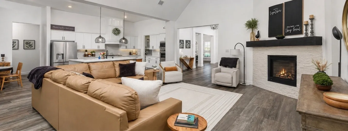 Vaulted ceilings with recessed lighting, wood-finish flooring, a contemporary fireplace with a stone surround, and an open-concept kitchen featuring stainless steel appliances