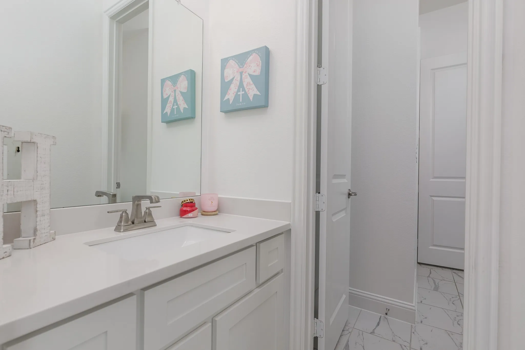 Bathroom vanity featuring a rectangular undermount sink, brushed nickel faucet, and white countertop
