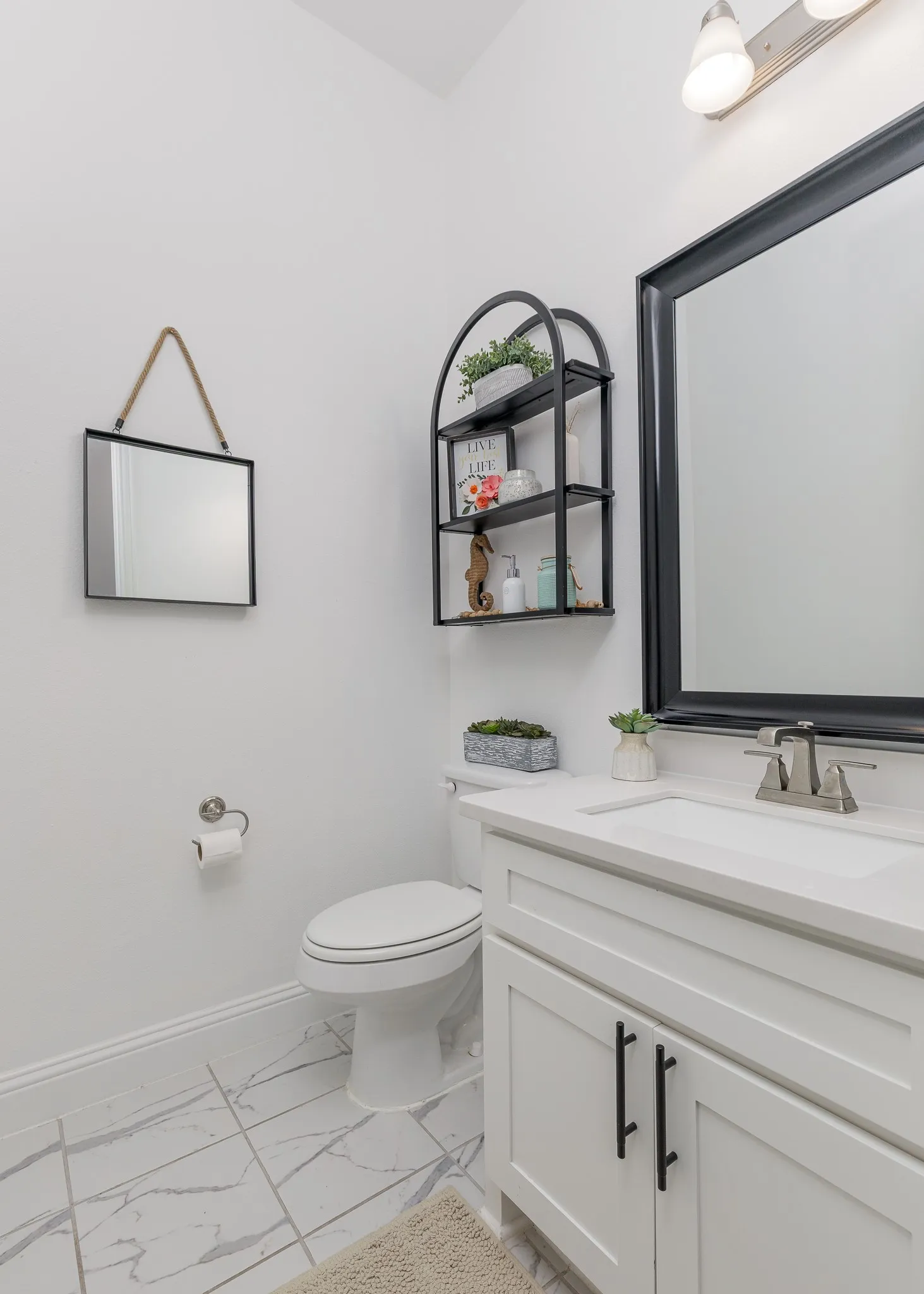 Bathroom featuring a single vanity with white cabinetry and black hardware