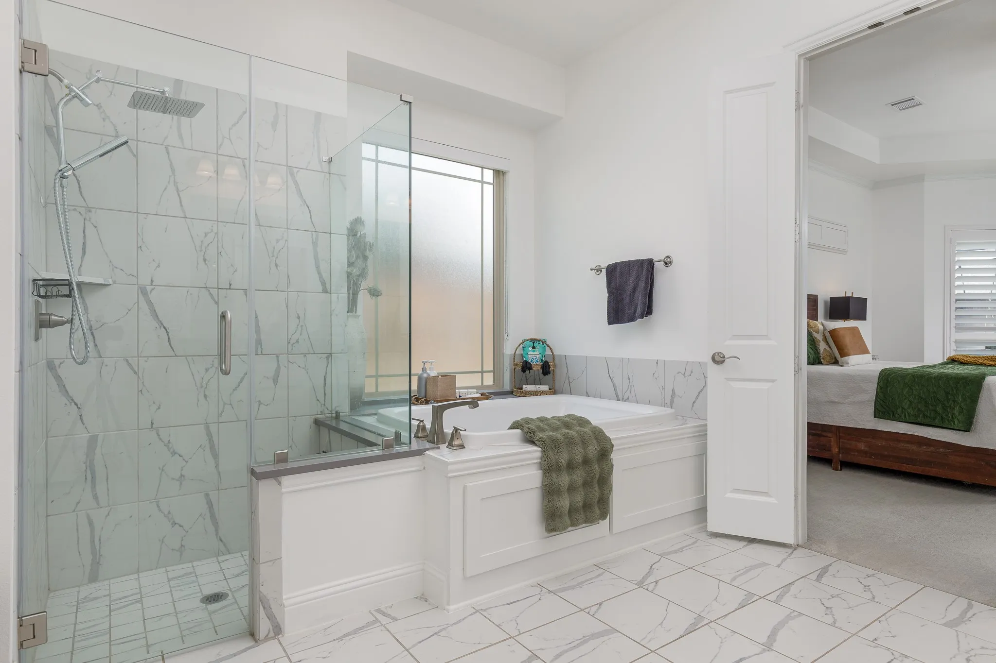 Spacious bathroom featuring a glass-enclosed shower with rain head and handheld fixtures, a built-in soaking tub, large format tile flooring, and a frosted privacy window