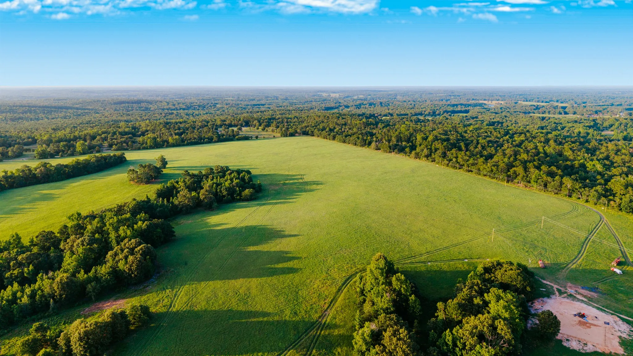 Expansive green fields bordered by mature woodlands