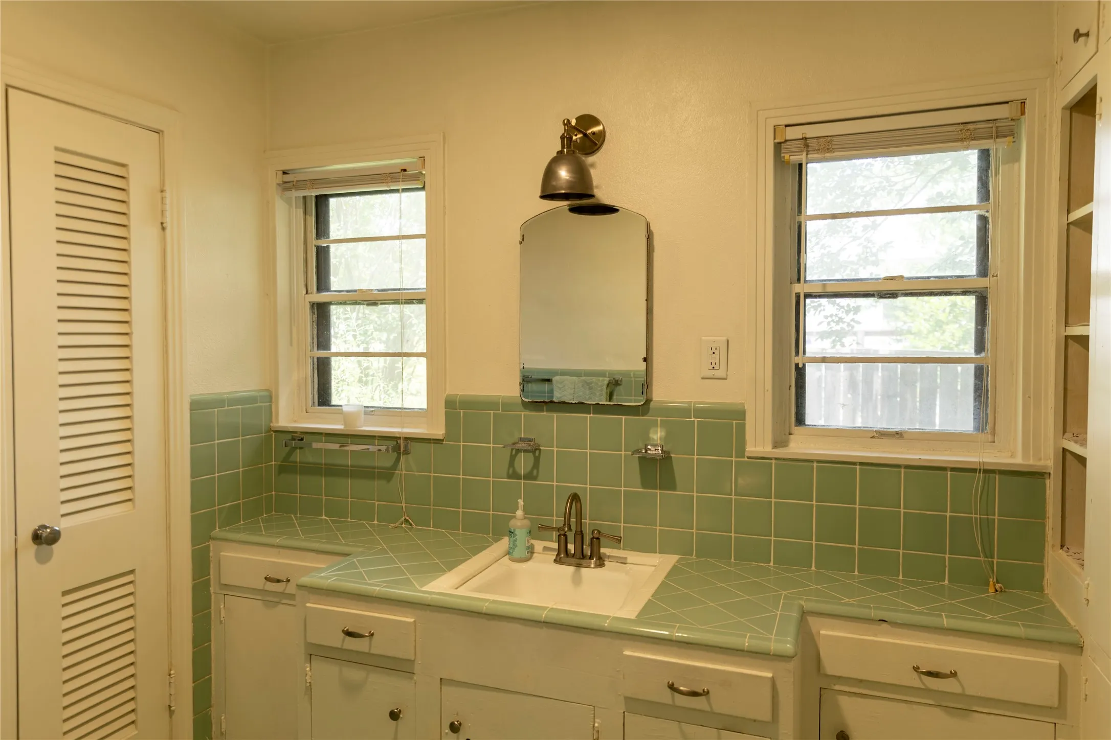 Bathroom vanity featuring an integrated sink, dual windows, and built-in storage cabinetry