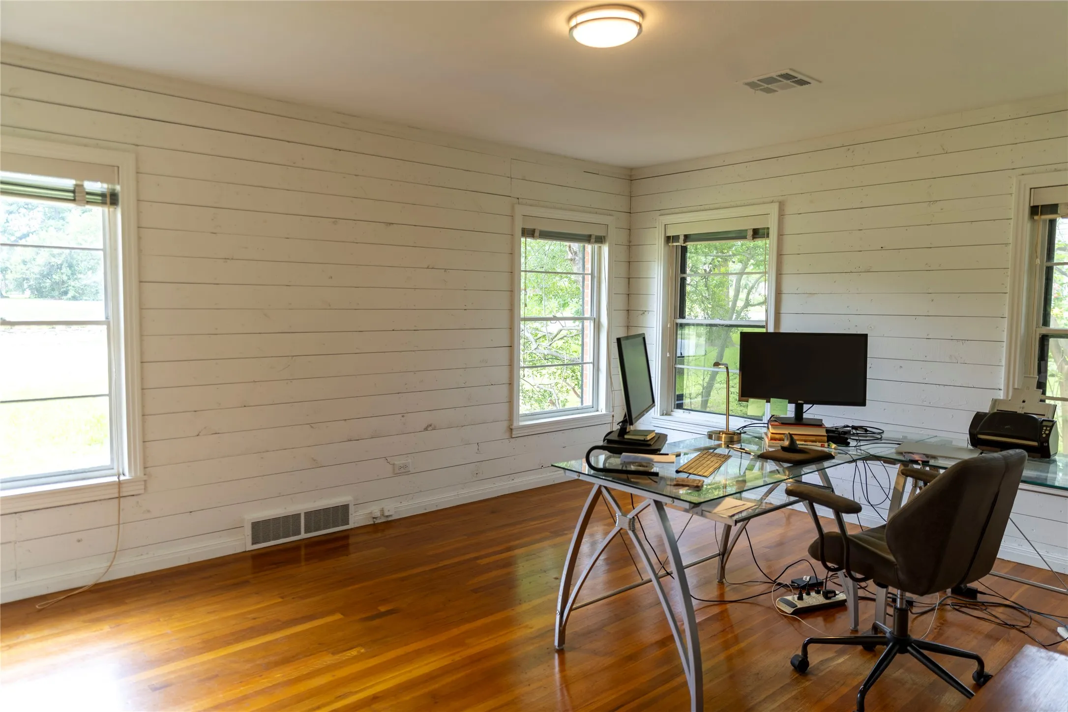 Room featuring wood-finish flooring, white shiplap walls, multiple windows, recessed lighting, and a ceiling-mounted light fixture