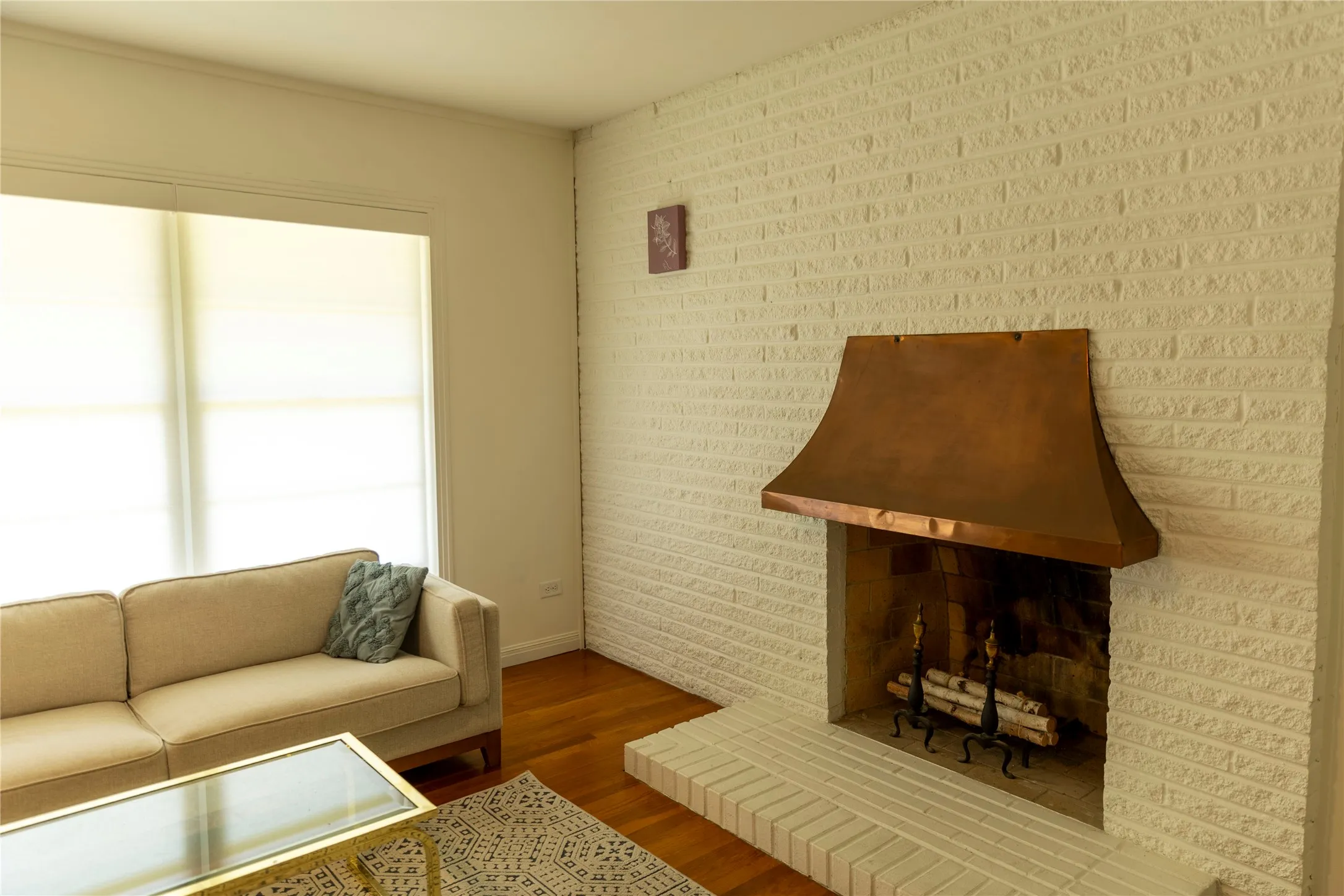 Living area featuring a painted brick fireplace with a copper hood and a brick hearth