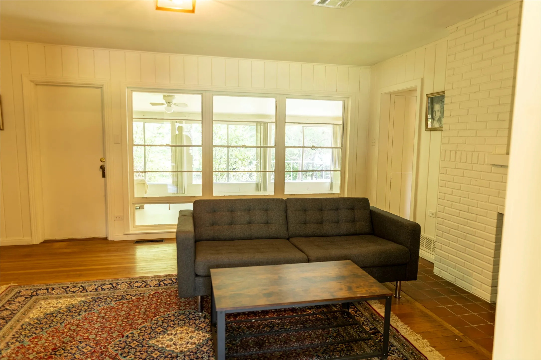 Spacious interior featuring a brick fireplace, wood-finish flooring, and expansive windows