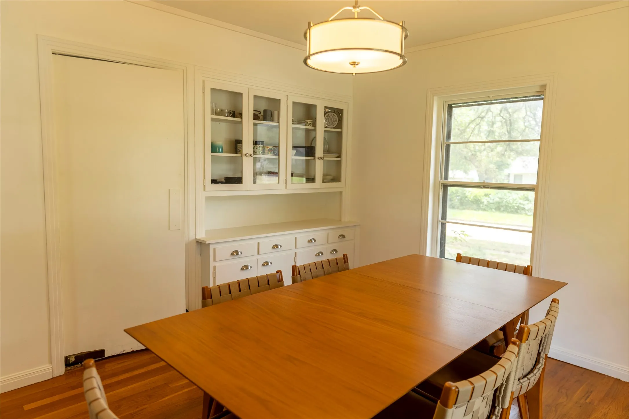 Dining space with wood-finish flooring, a built-in china cabinet with glass-front uppers, and a single window