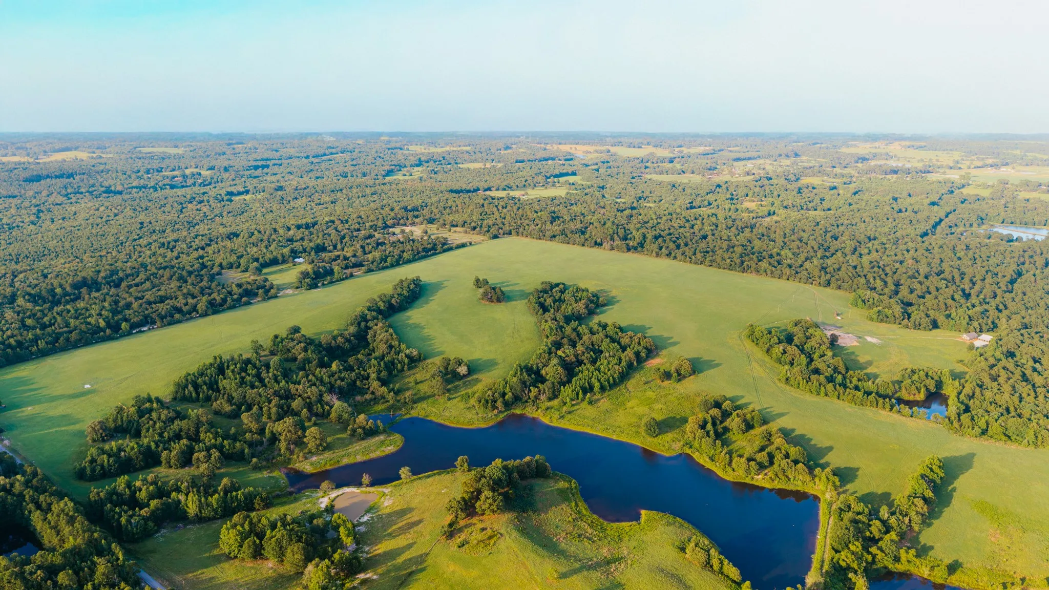 Expansive property featuring a large body of water, open pastures, and wooded​​‌​​​​‌​​‌‌​‌‌​​​‌‌​‌​‌​‌​​​‌​​ areas