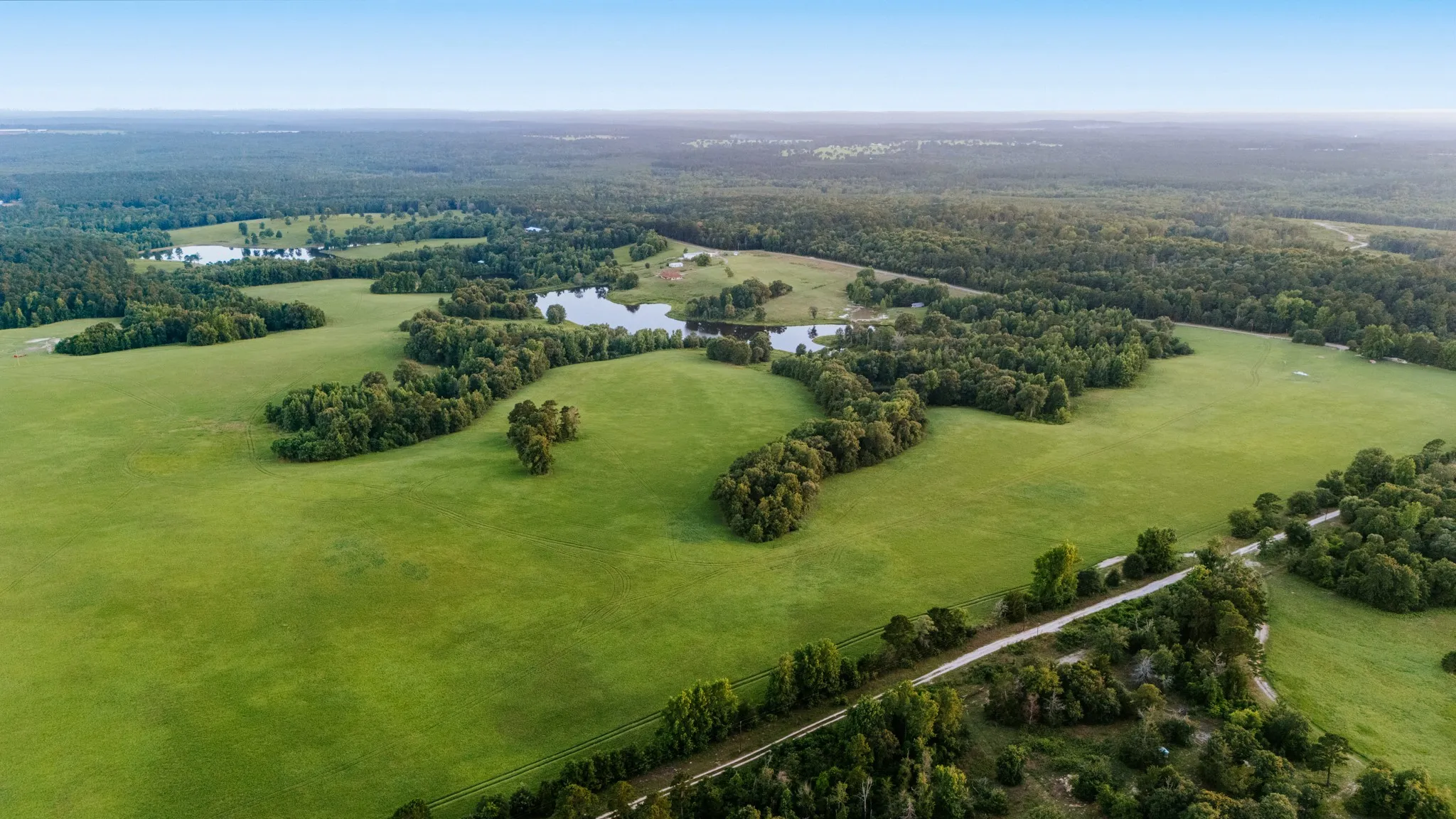 Expansive green fields, multiple ponds, and mature tree lines define this property