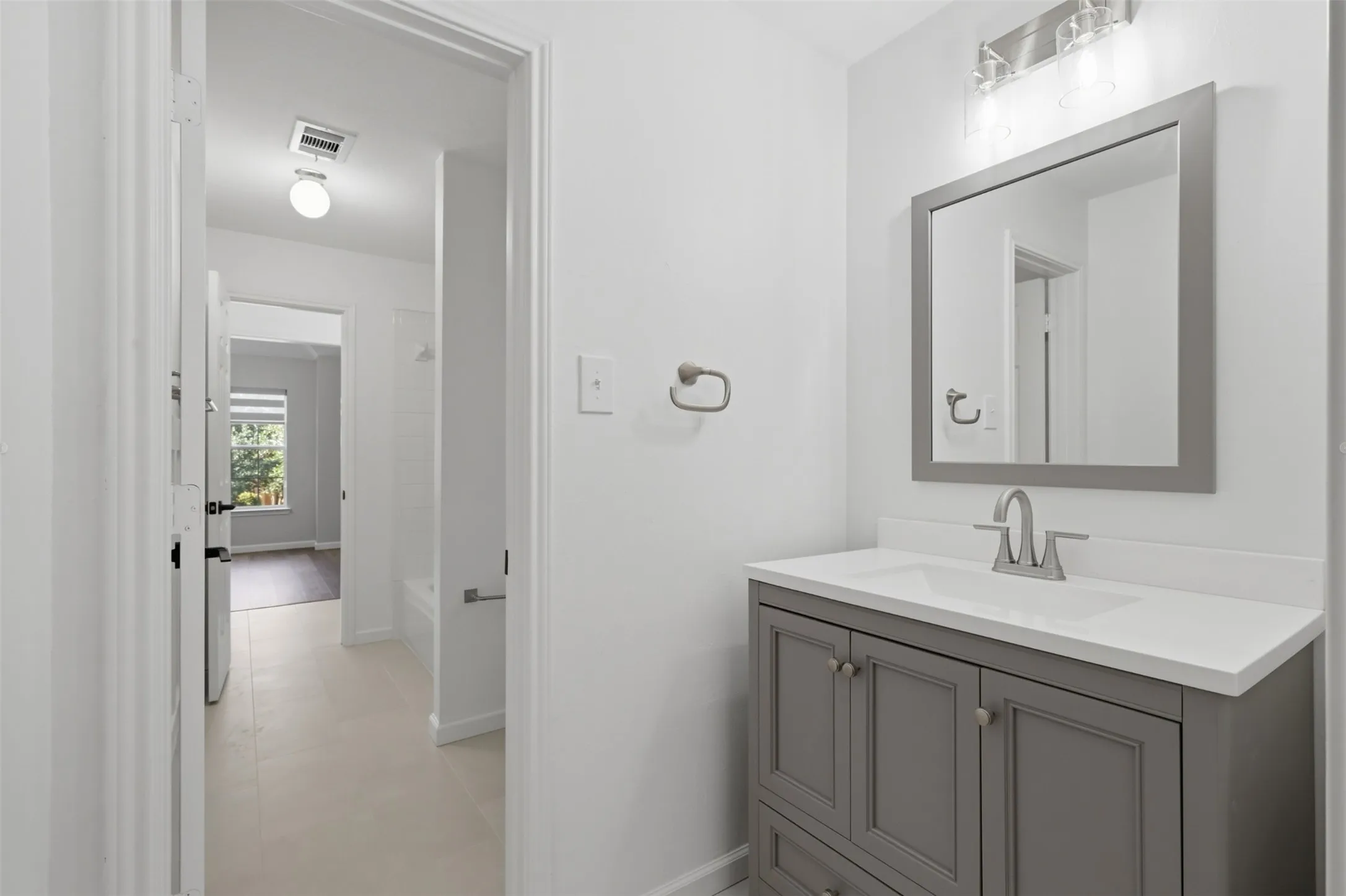 Bathroom featuring a grey vanity with a white countertop, undermount sink, and a framed mirror