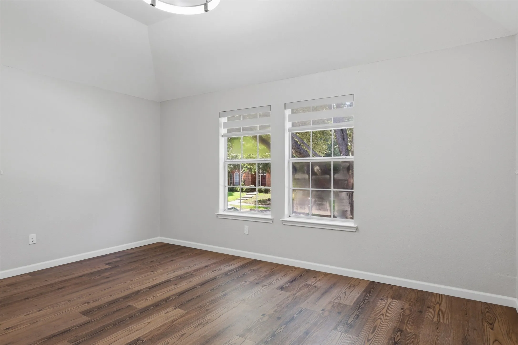 Spacious room featuring wood-finish flooring, light gray walls, and white baseboards