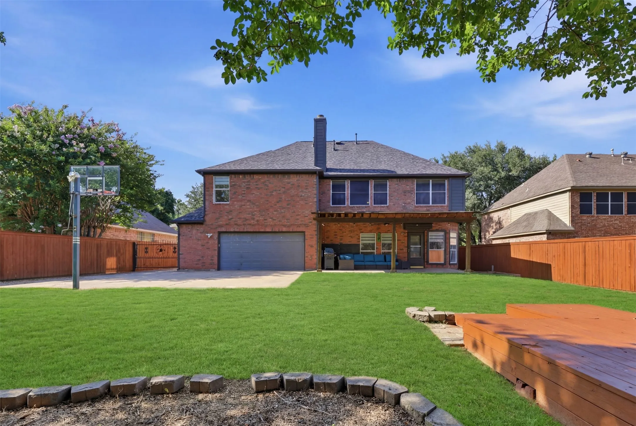 Expansive backyard featuring a manicured lawn, a wood deck, and a full-height privacy fence