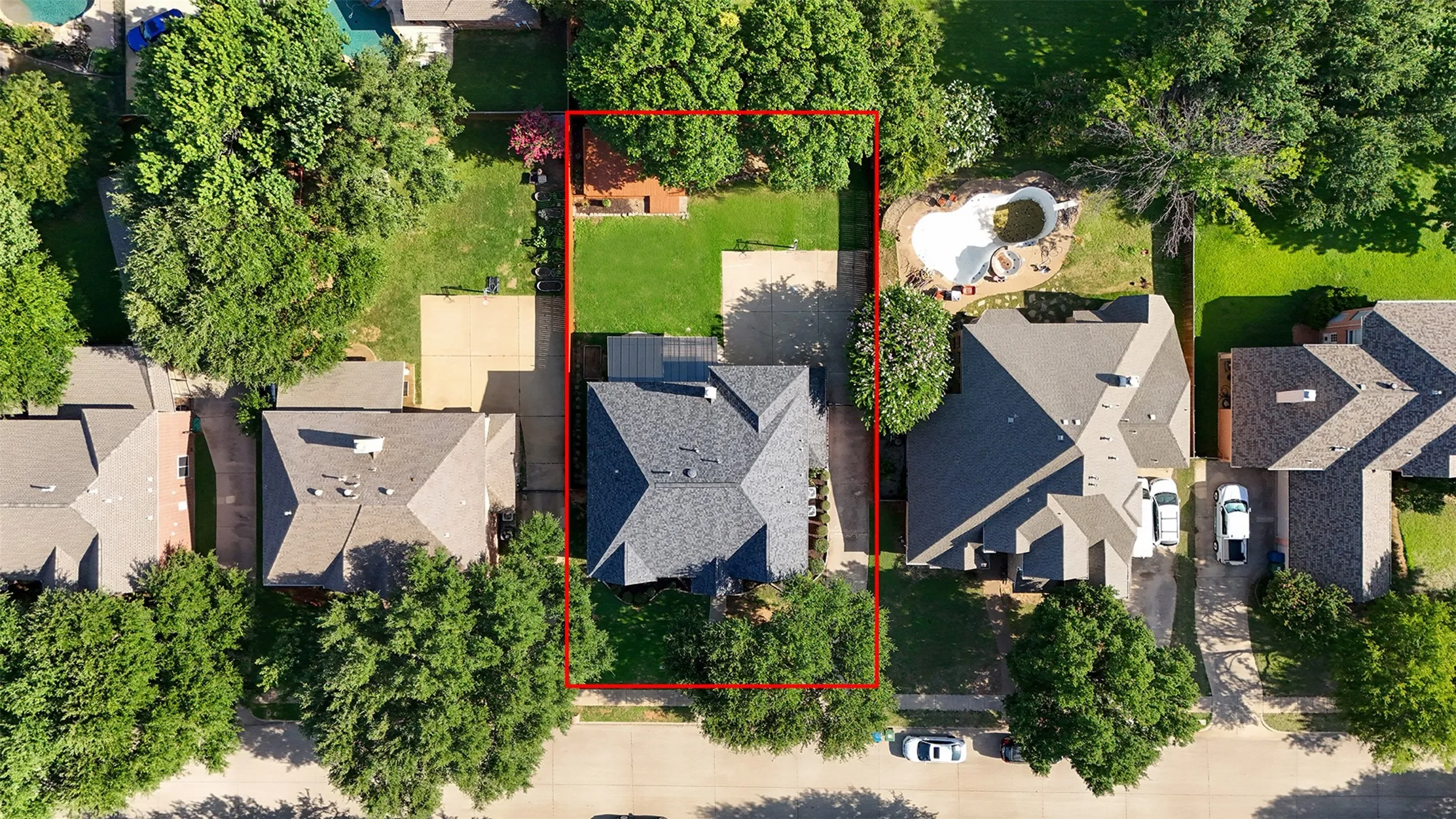 Aerial property outline showcasing a traditional-style residence with a dark shingle roof, a front-facing driveway, and established surrounding trees