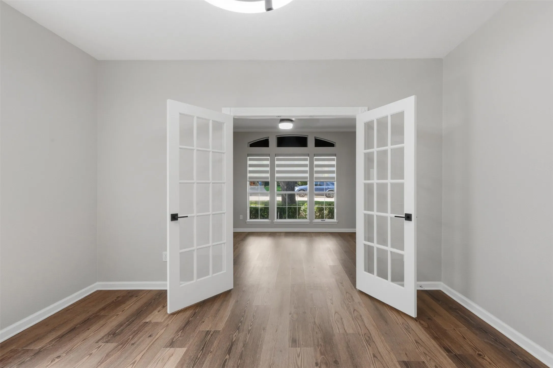 Room featuring wood-finish flooring, light grey painted walls, and white baseboards