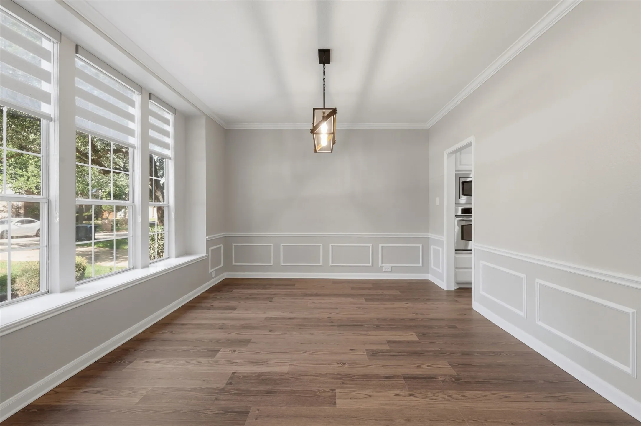 Spacious interior featuring wood-finish flooring, wainscoting, and crown molding