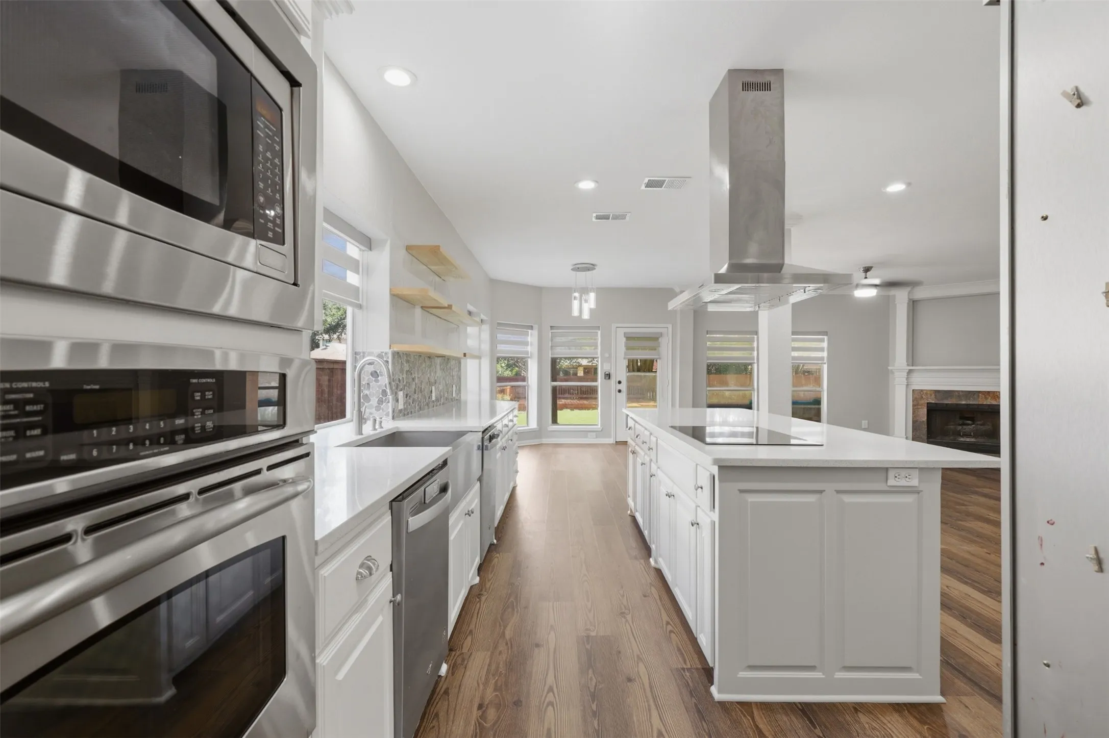 Contemporary kitchen featuring wood-finish flooring, white cabinetry, and stainless steel appliances