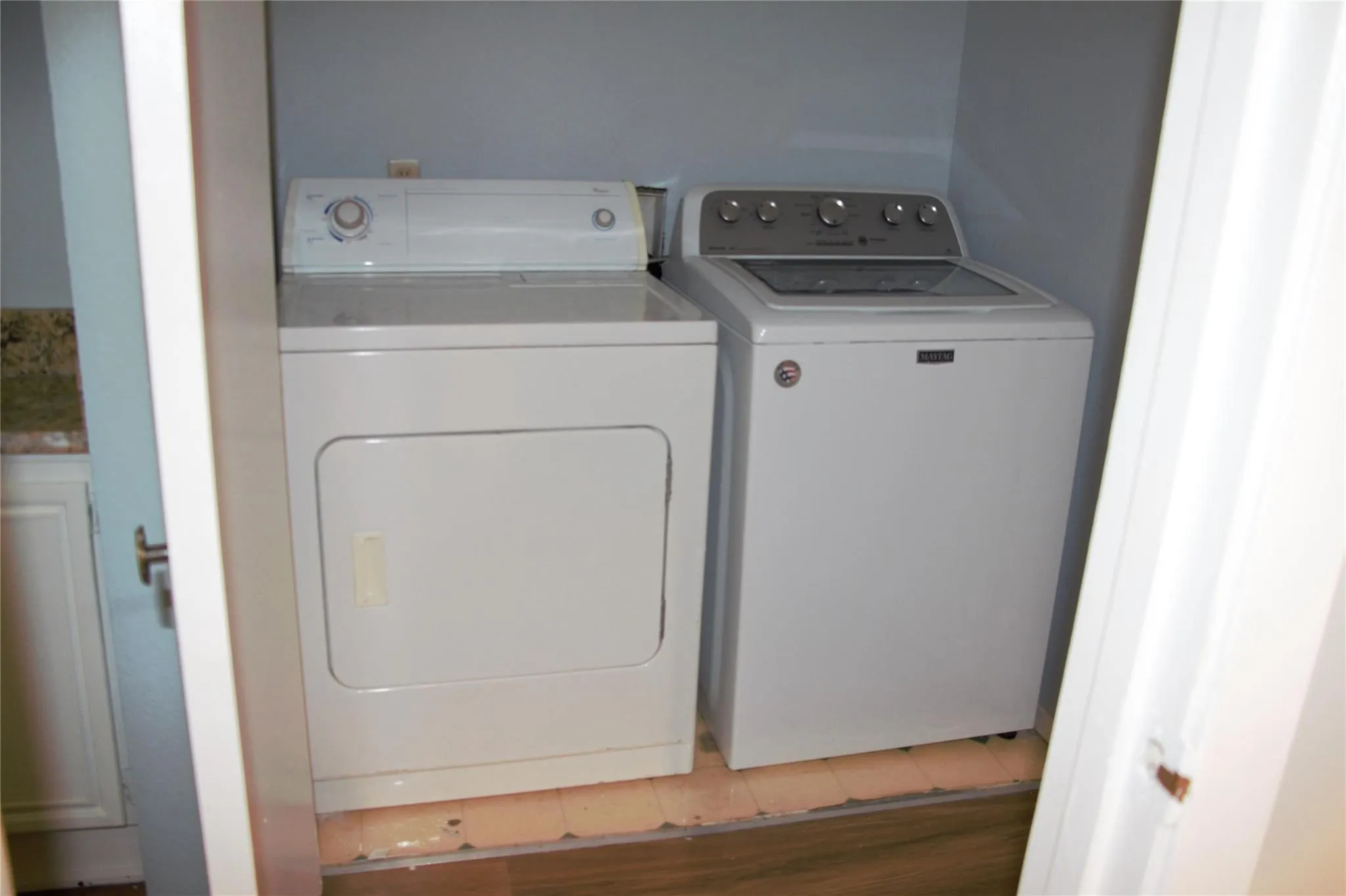 Clothes washing area with separate washer and dryer and wood-type flooring