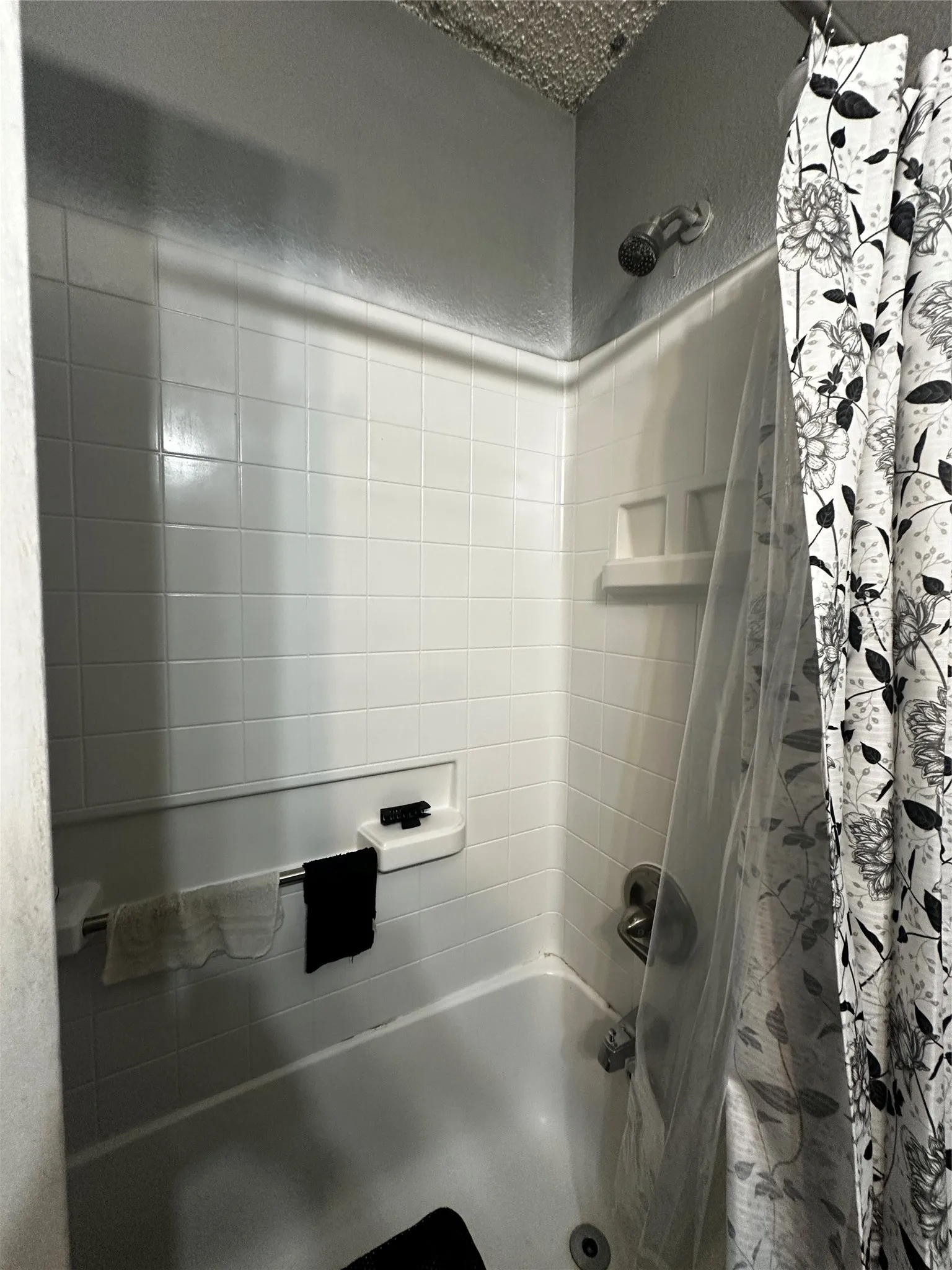 Bathtub shower combination featuring white subway tile surround