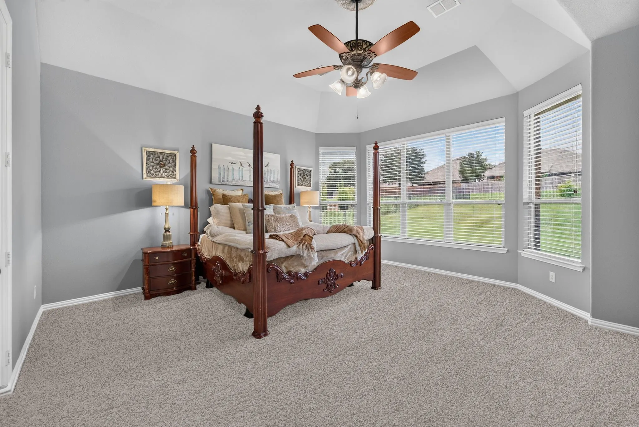 Spacious room featuring vaulted ceilings, light gray wall paint, and plush carpeting