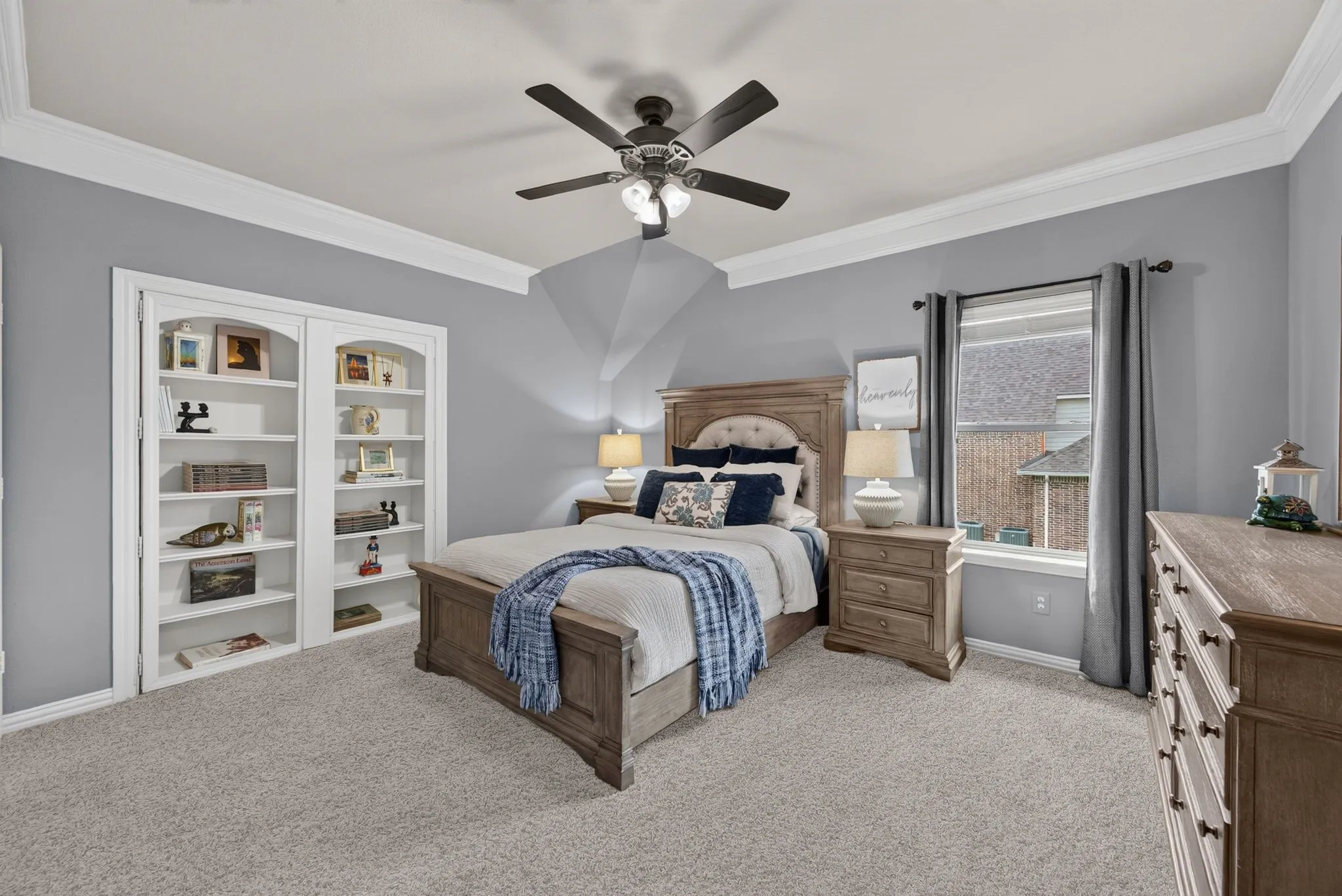 Carpeted room featuring integrated built-in shelving, crown molding, and a ceiling fan with integrated lighting