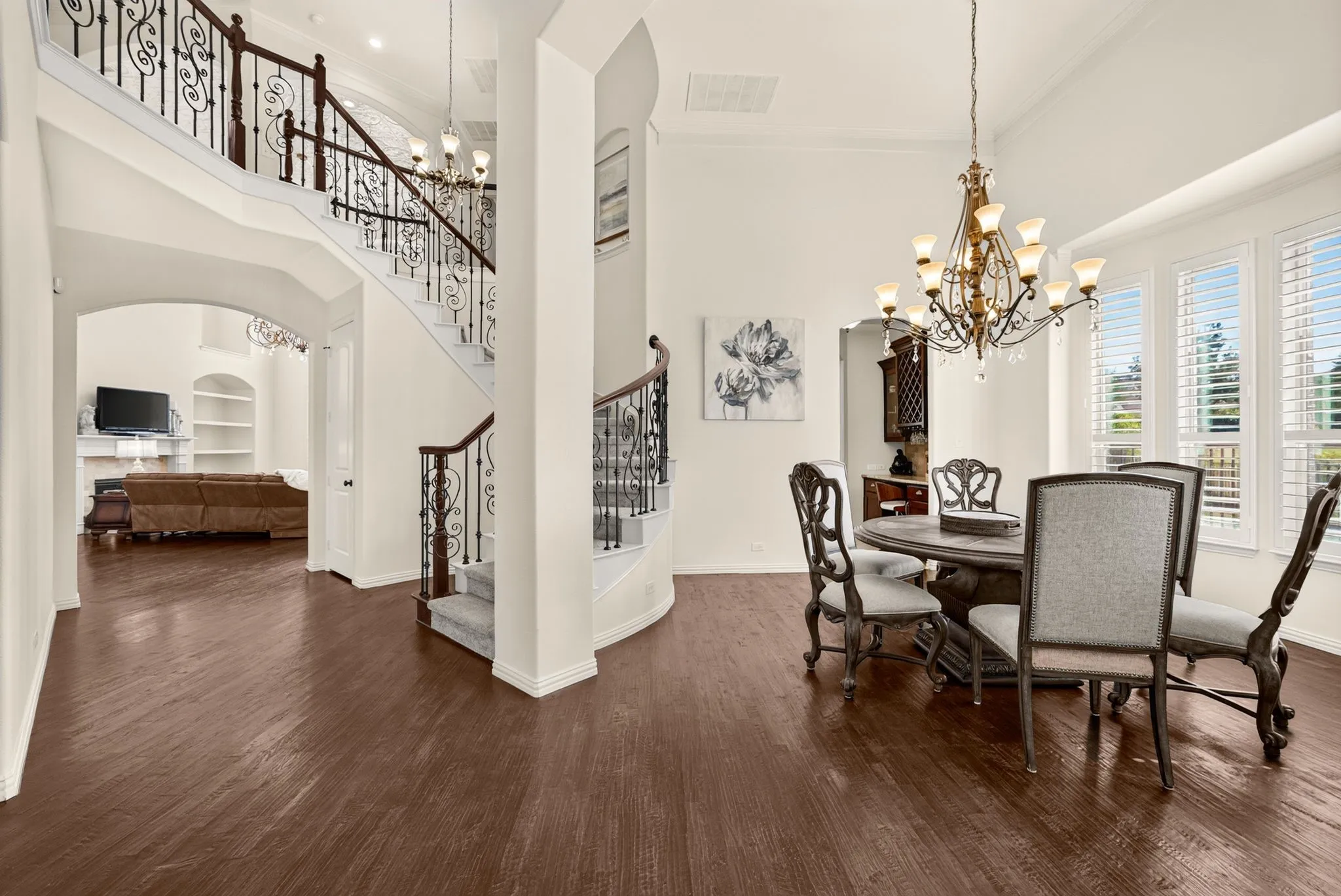 Wood-finish flooring throughout, wrought iron staircase with wood handrails, vaulted ceiling, built-in shelving, and plantation shutters