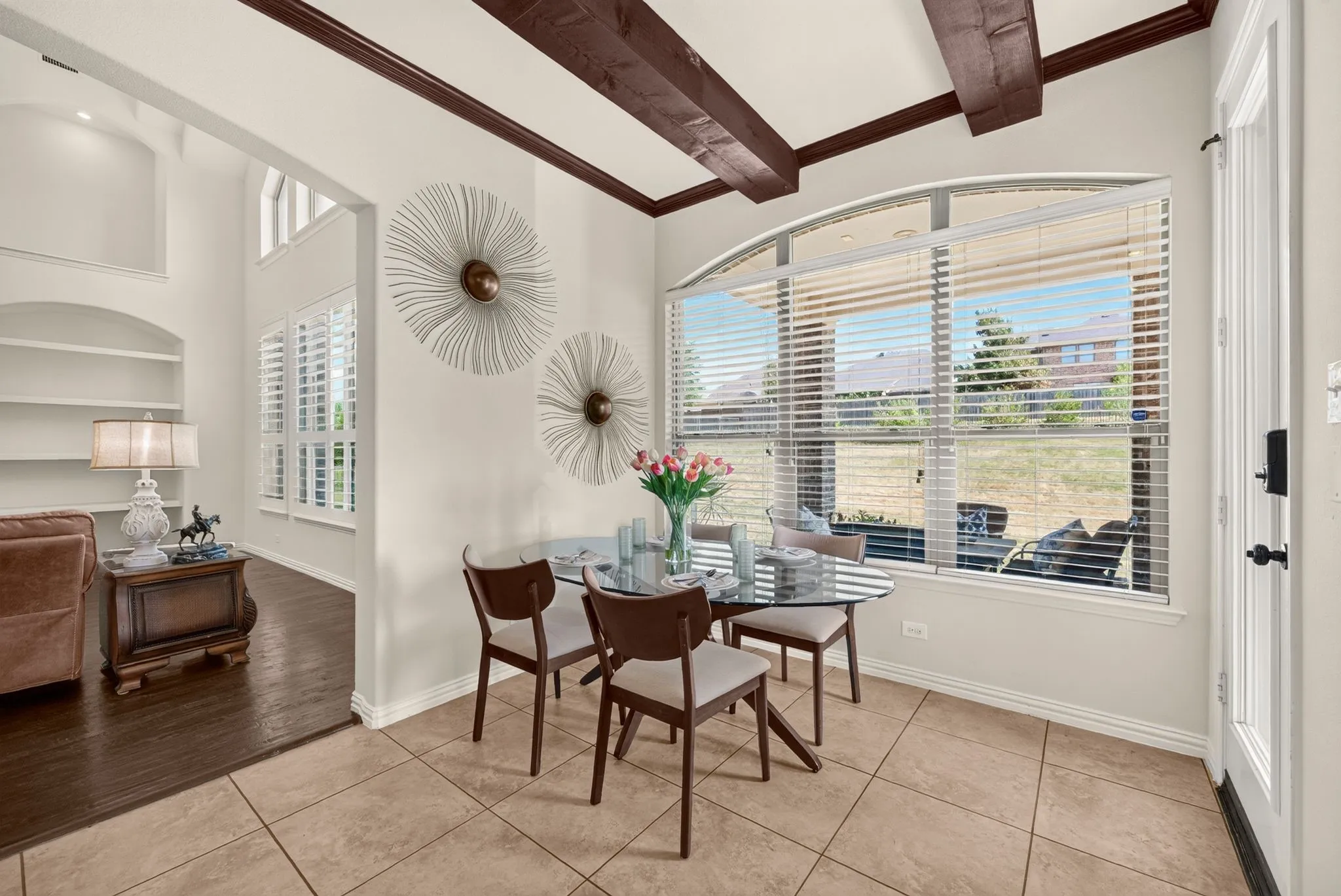 Dining area featuring an arched window, exposed ceiling beams, and tile flooring