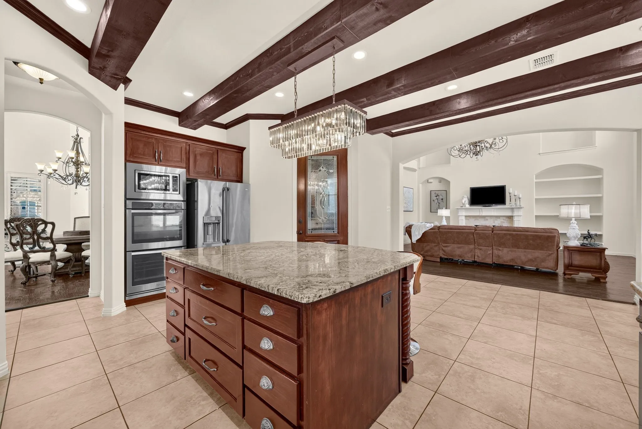 Kitchen featuring a center island with granite countertop, wood-finish cabinetry, stainless steel double ovens, and tile flooring