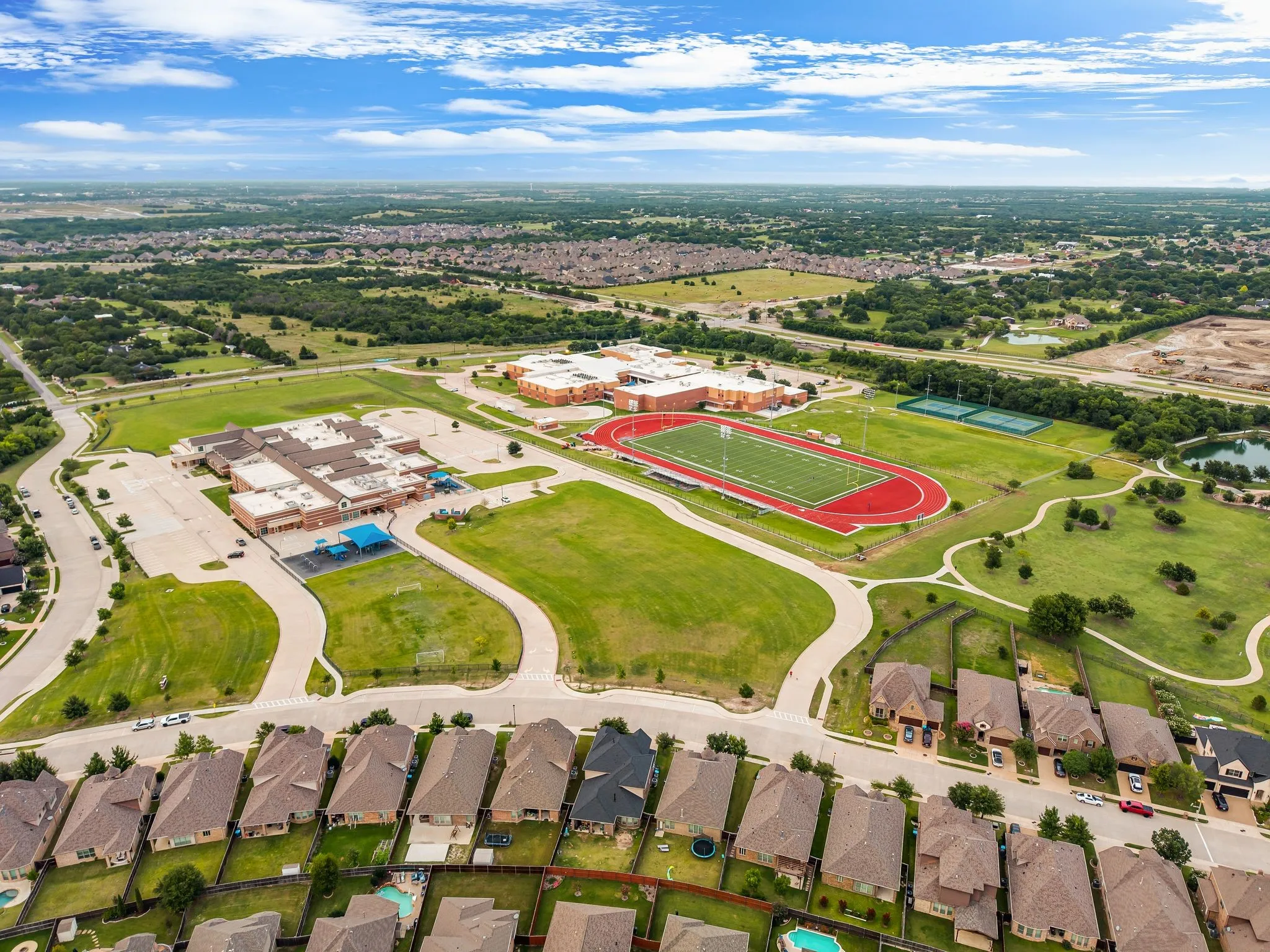 Aerial perspective showcasing residential properties bordering a community with extensive green spaces