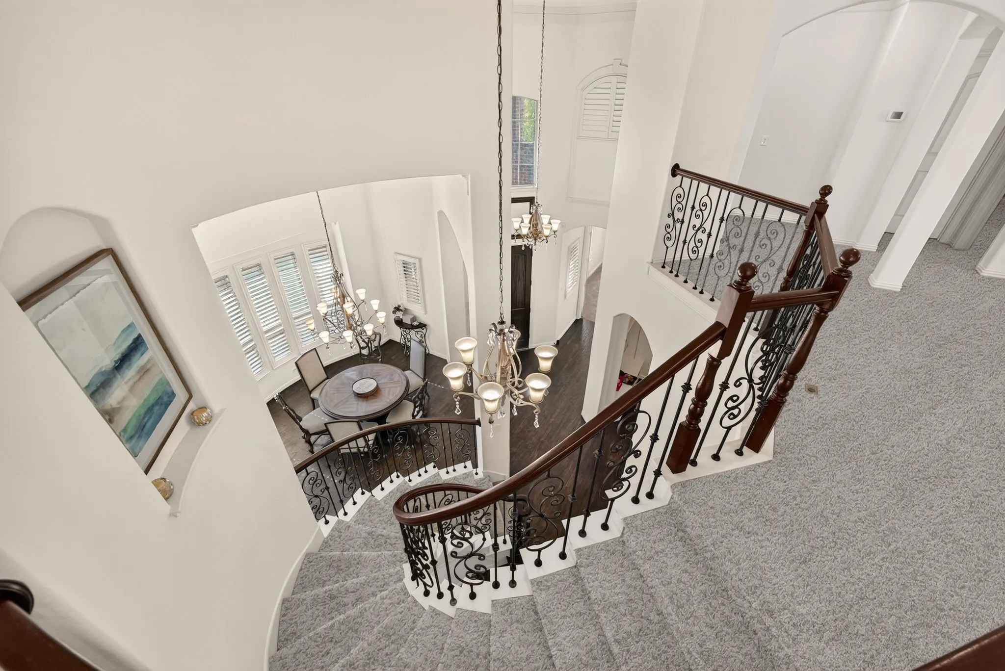 Curved staircase with wood handrail and wrought iron balusters, high ceilings, arched doorways, and a chandelier