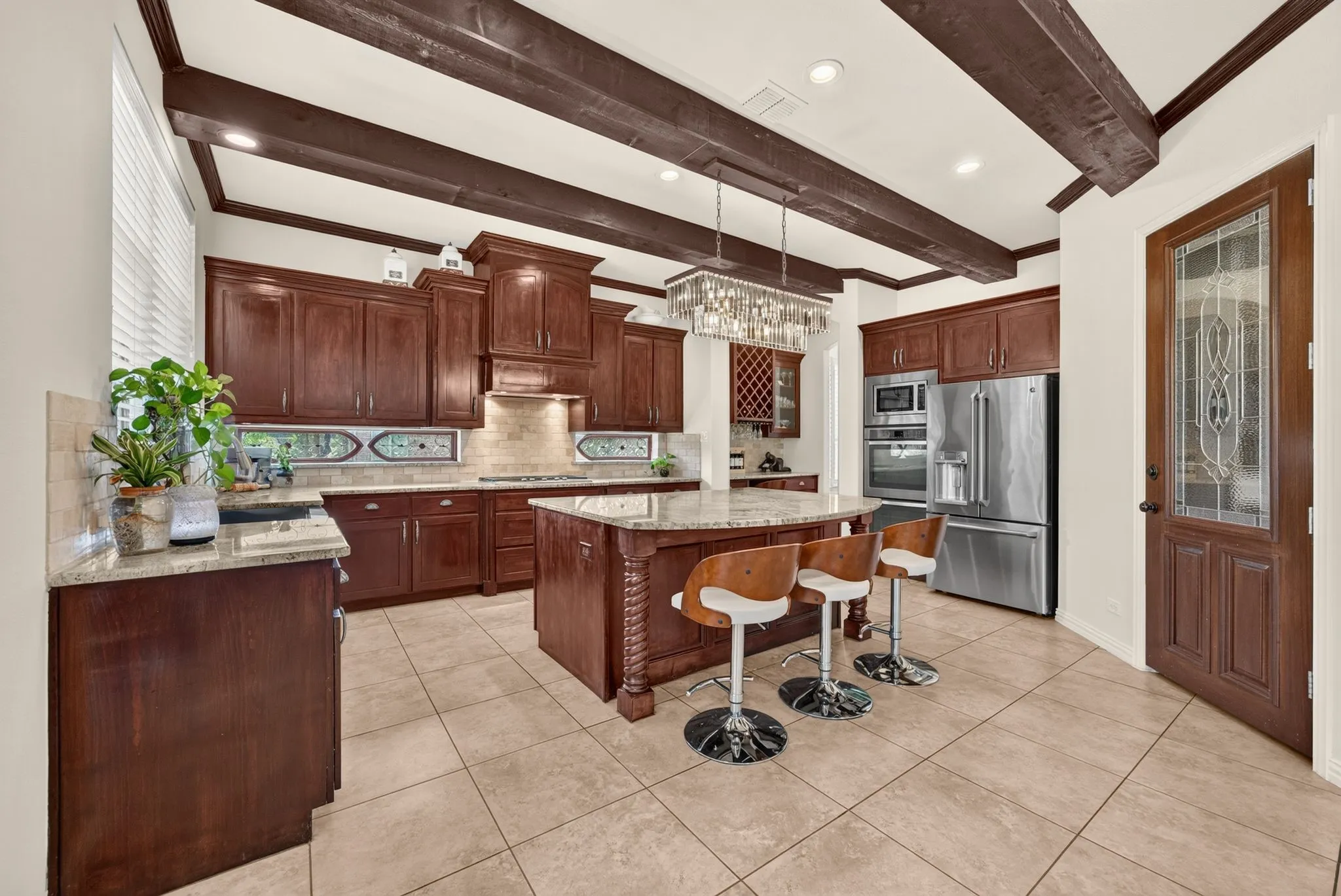 Kitchen with exposed ceiling beams, recessed lighting, wood cabinetry, granite countertops, and stainless steel appliances