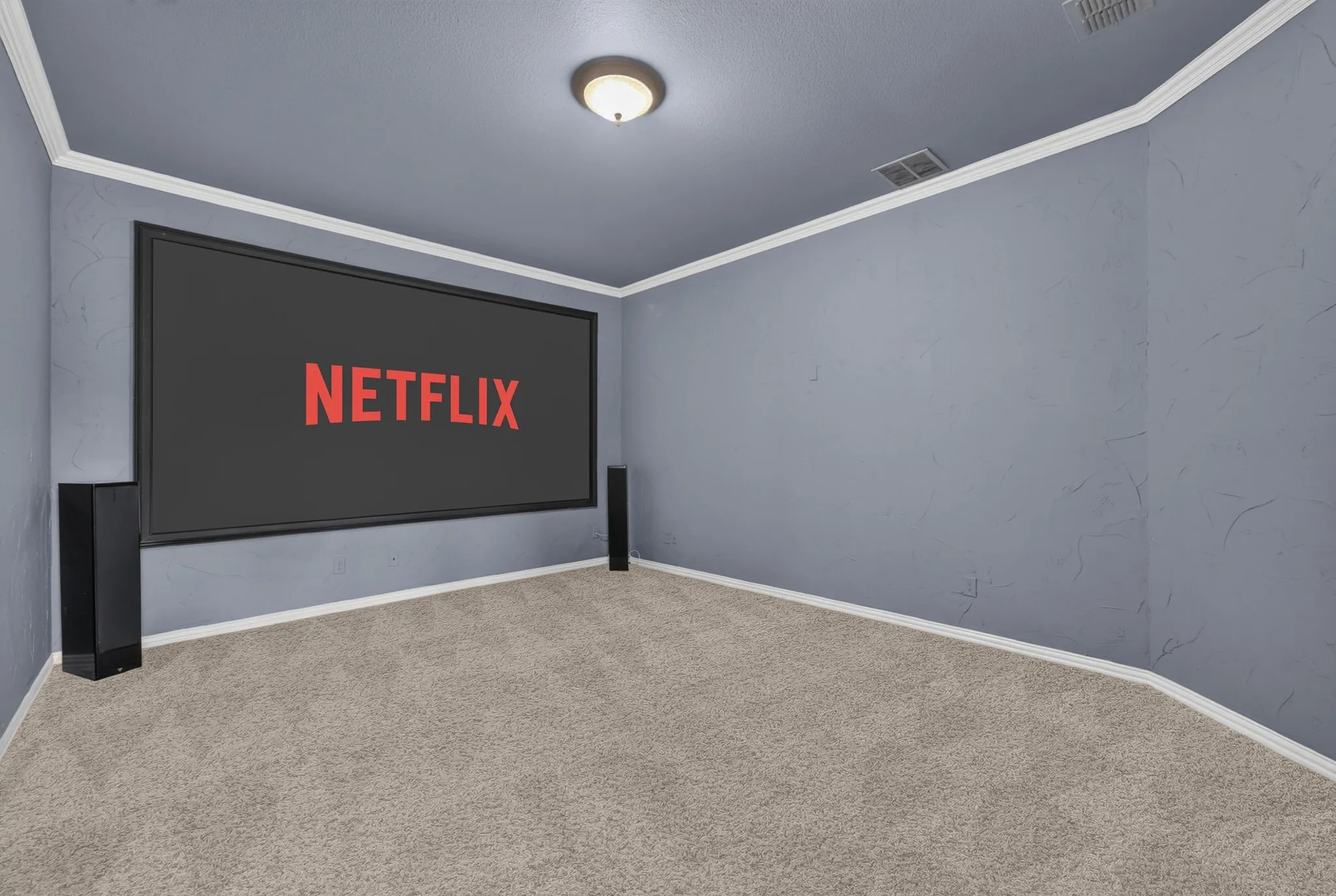 Dedicated media room featuring a large projection screen, two integrated sound towers, textured blue-gray walls, neutral carpeting, and white crown molding