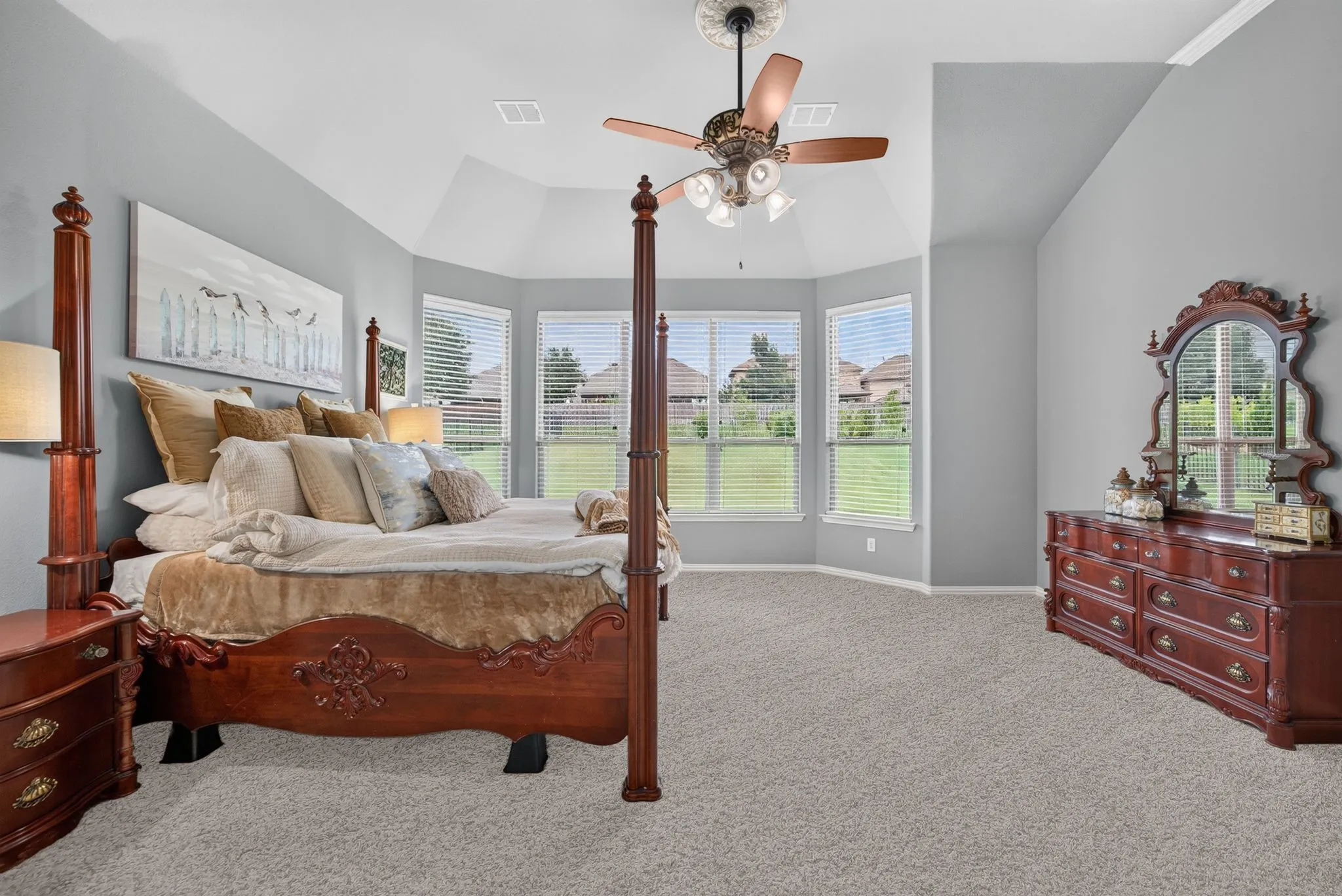 Spacious room featuring vaulted ceilings, a bay window with blinds, light gray wall paint, and gray carpet flooring
