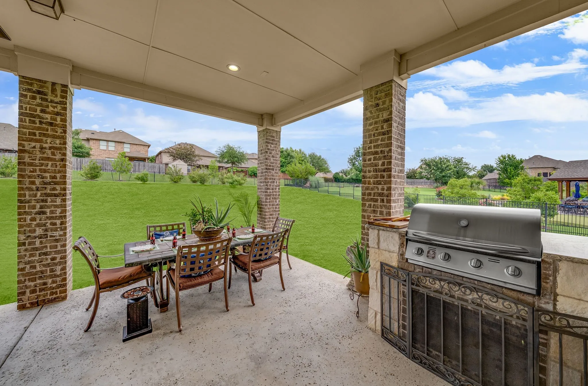 Covered patio featuring an integrated built-in grill, stone counter space, and brick columns