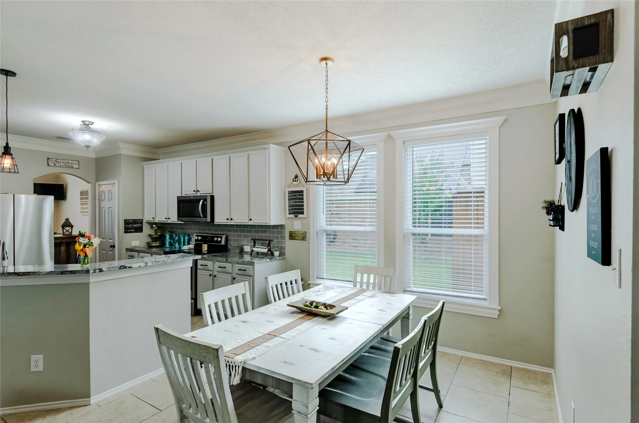 Kitchen and dining area featuring light-toned cabinetry, a subway tile backsplash, and crown-molding.