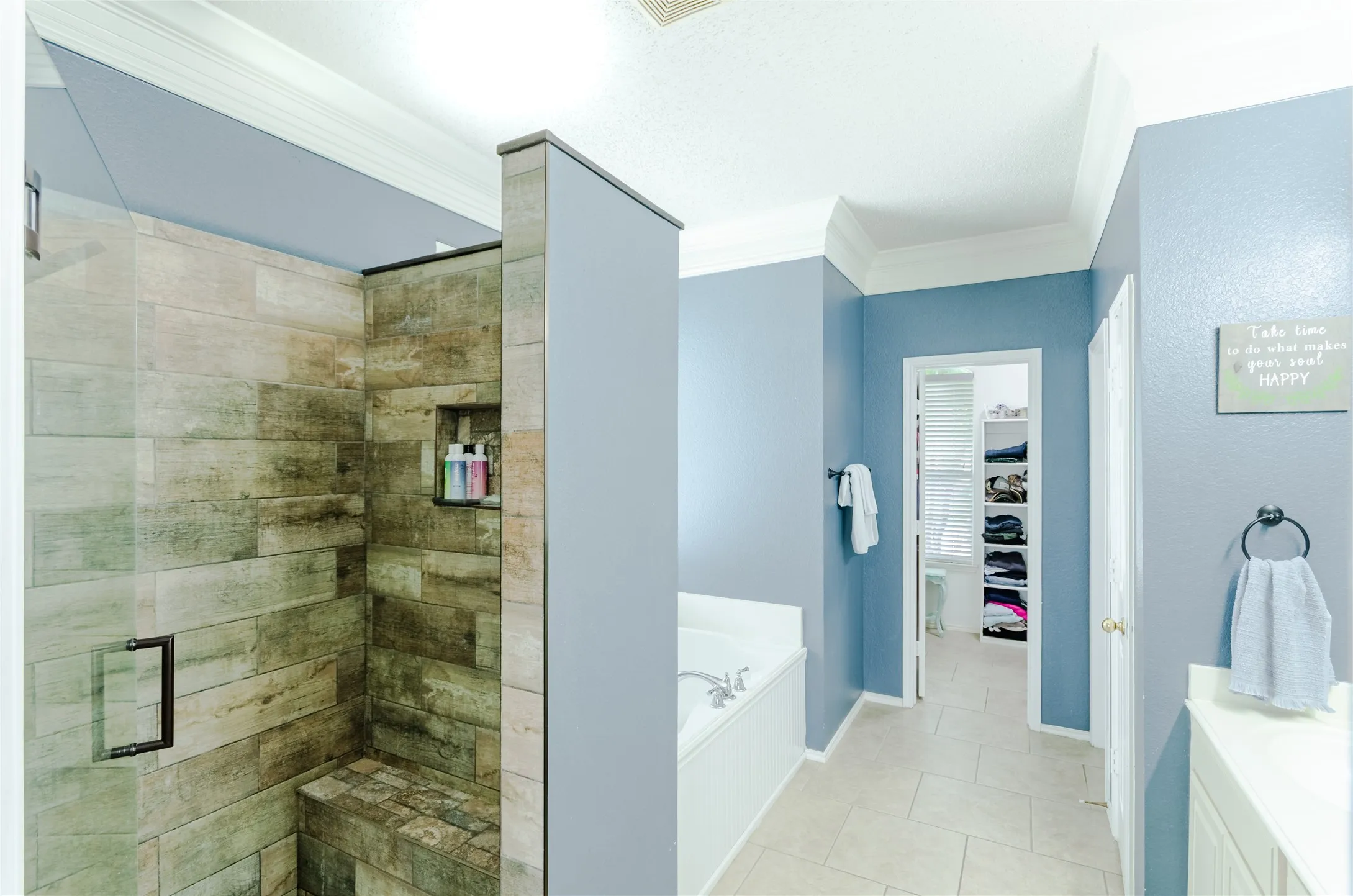 Glass-enclosed shower with wood-look tile, frameless glass door, built-in bench, and recessed niche
