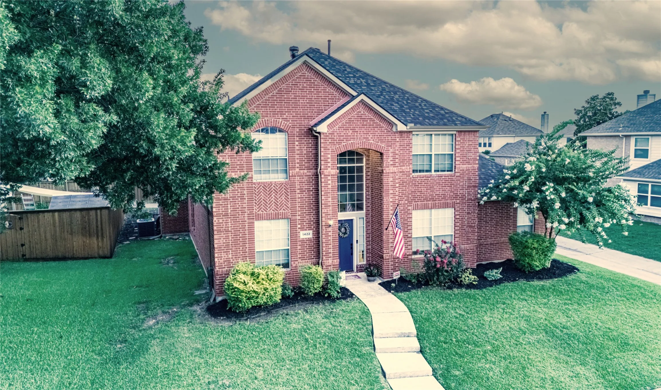 Brick facade residence featuring a prominent two-story entry with arched window accents, a dark blue front door, and a concrete pathway