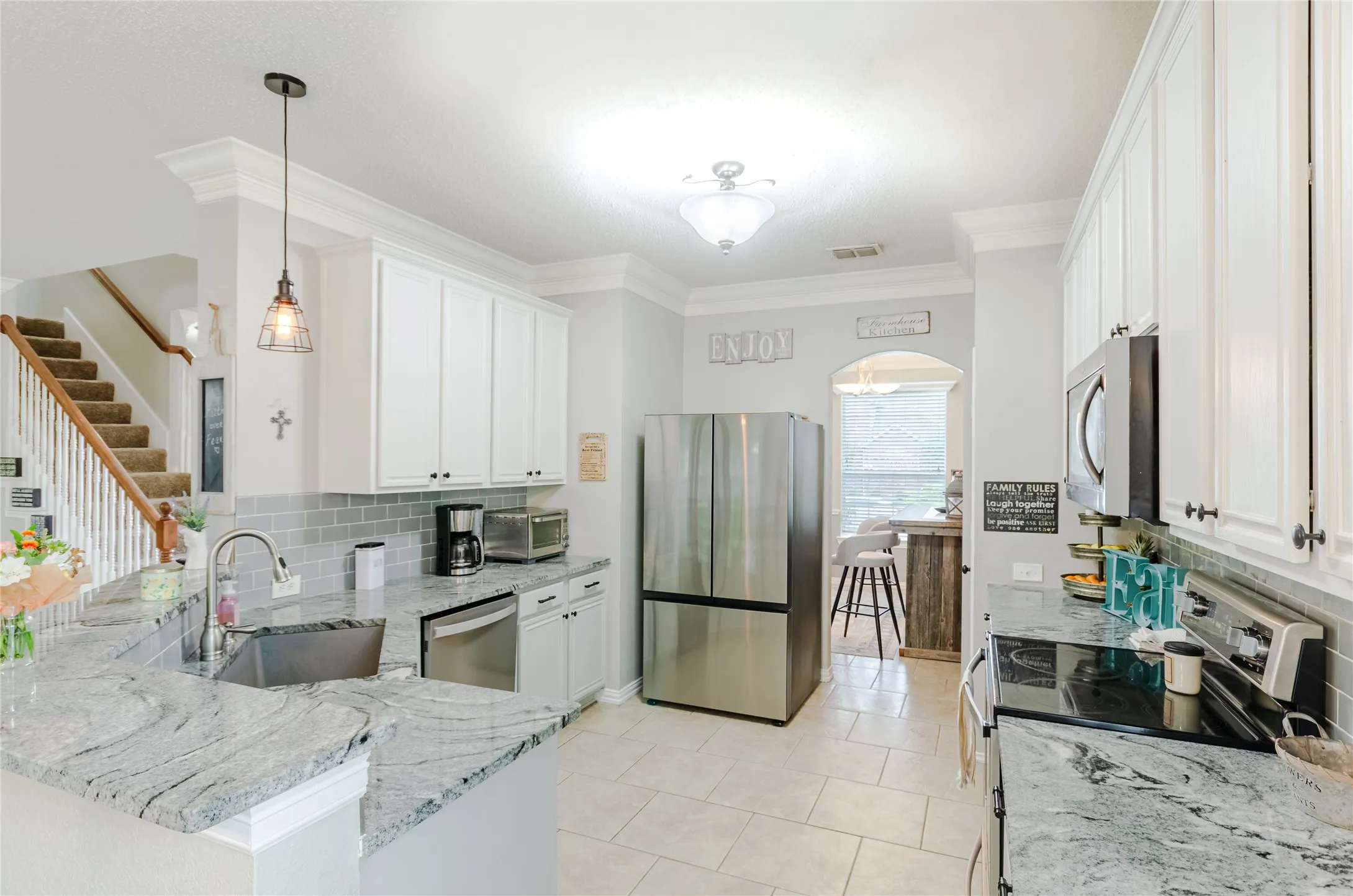 Kitchen featuring light cabinetry, gray subway tile backsplash, stainless steel appliances, and granite countertops