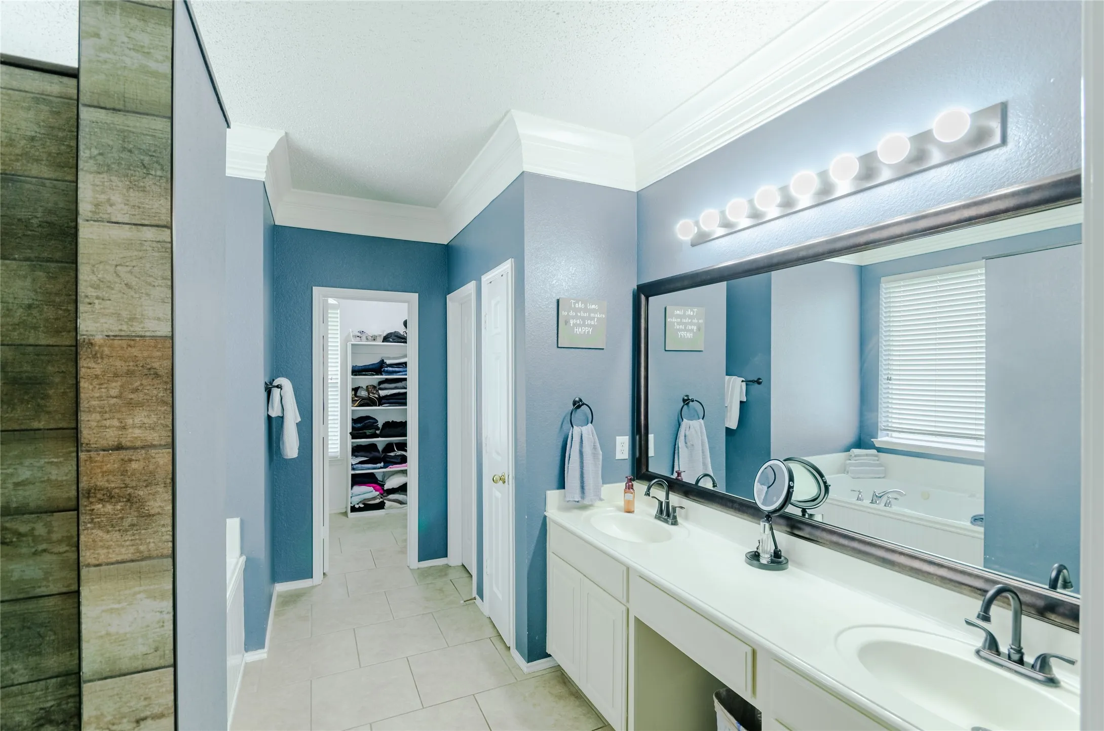 Spacious bathroom featuring a dual vanity, large wall mirror, and a built-in makeup counter