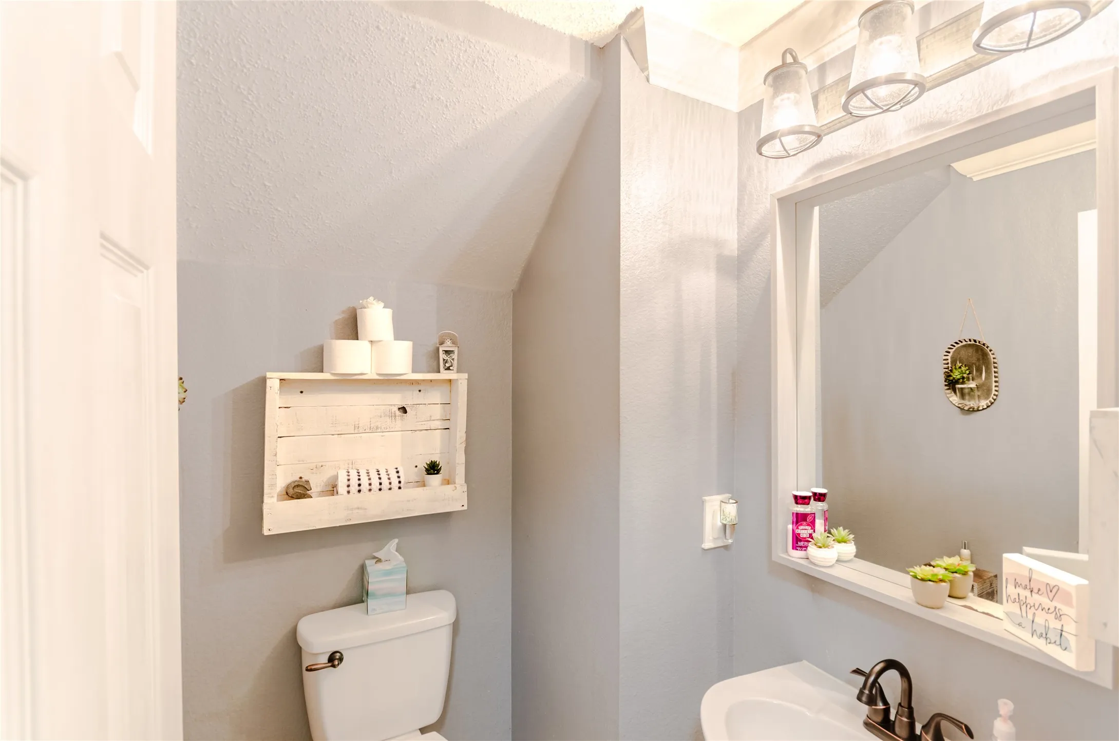 Half Bath featuring a pedestal sink, framed mirror, and a three-light vanity fixture