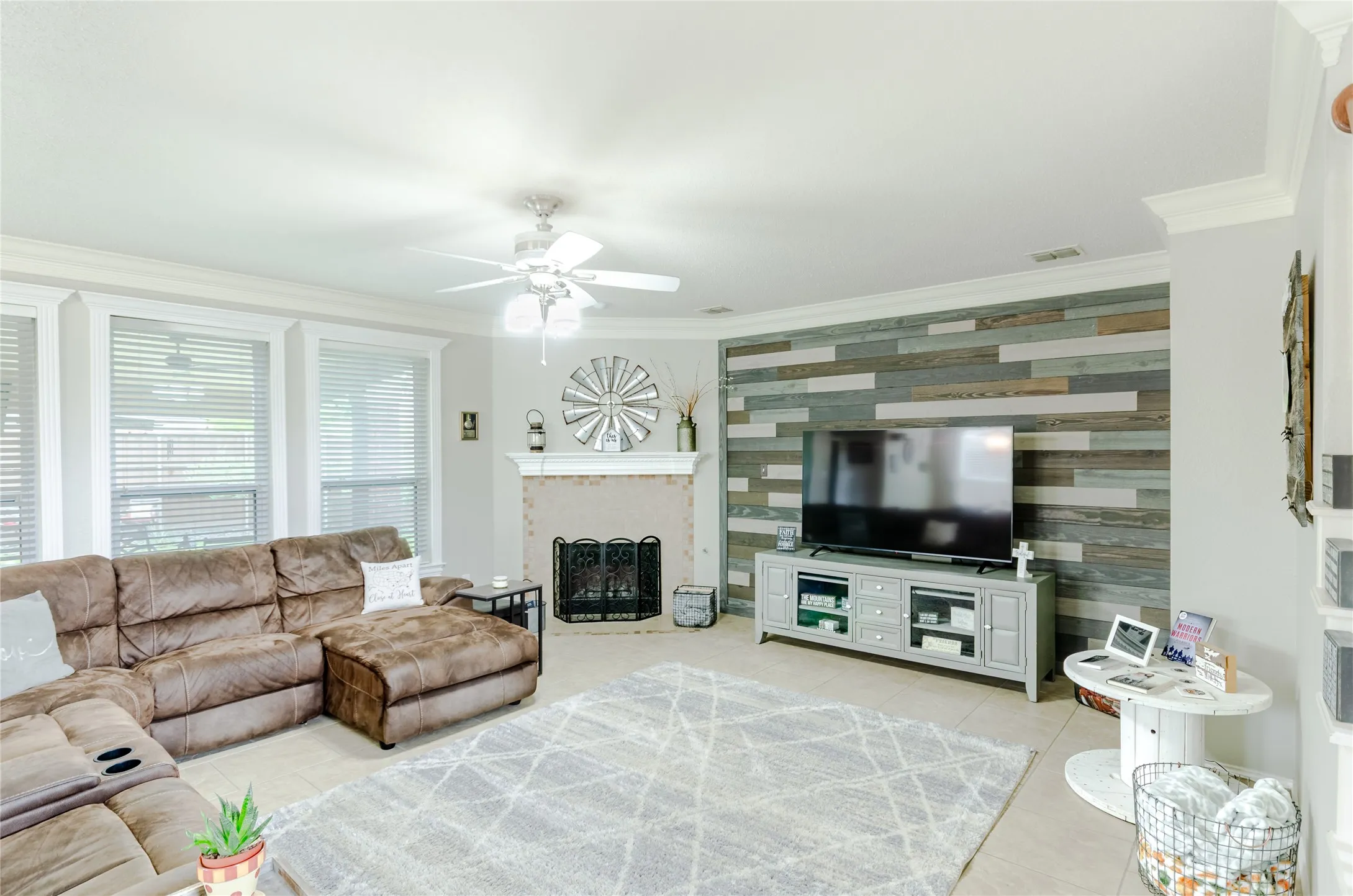 Living area featuring a textured accent wall, fireplace with metal screen, and multiple windows with blinds
