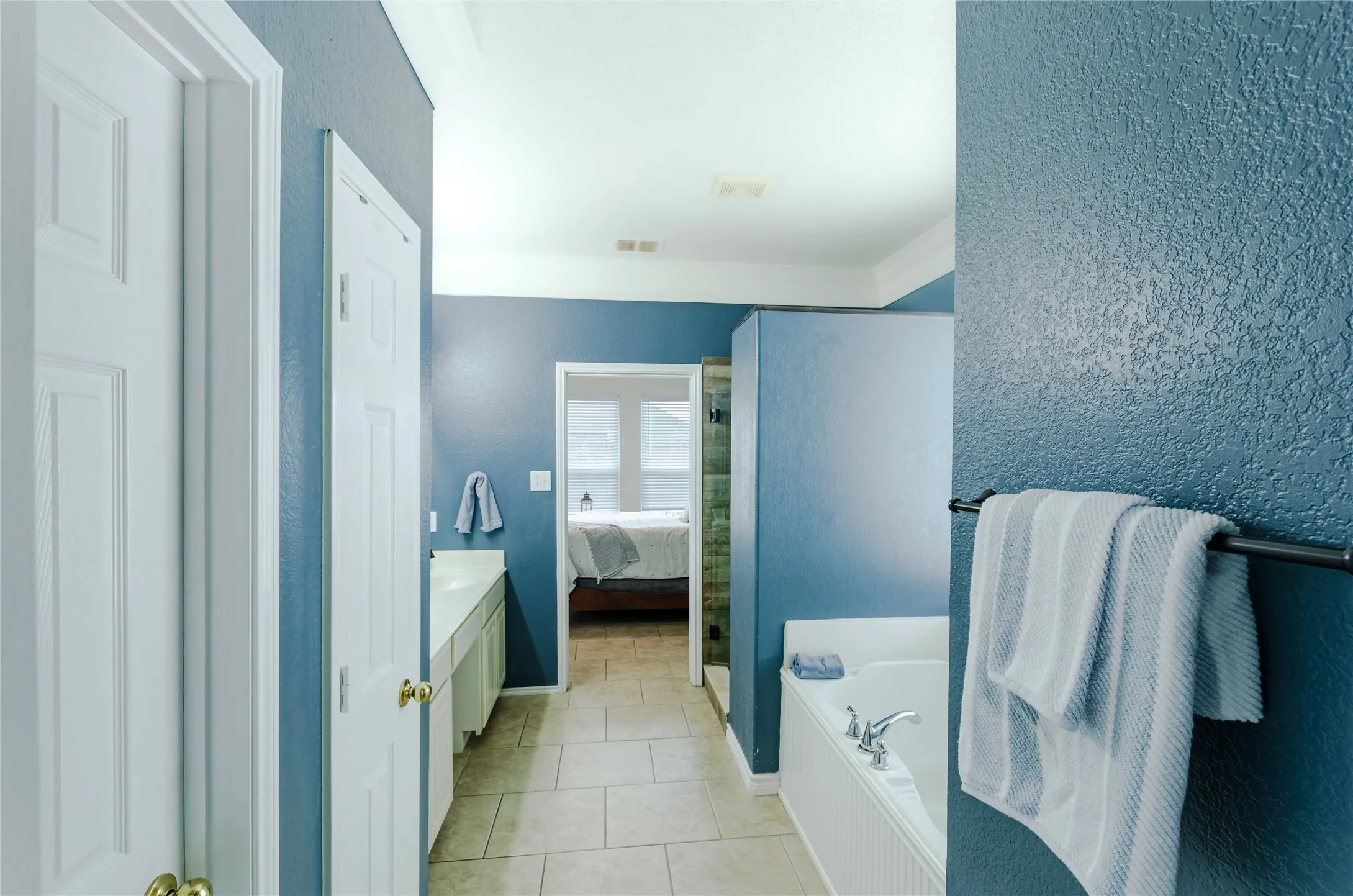 Bathroom featuring a jetted tub with a tile surround, dual vanity with dual sinks, and tile flooring